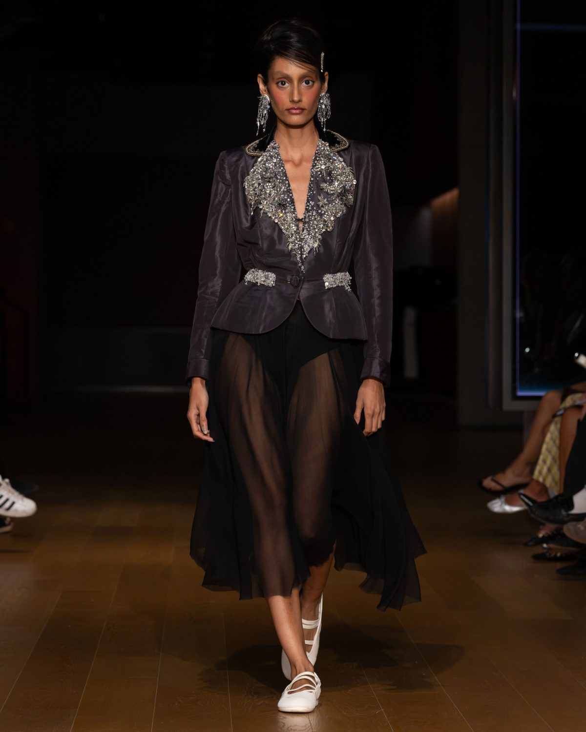 Dark grey embellished peplum jacket with a sheer black midi skirt and white flats.