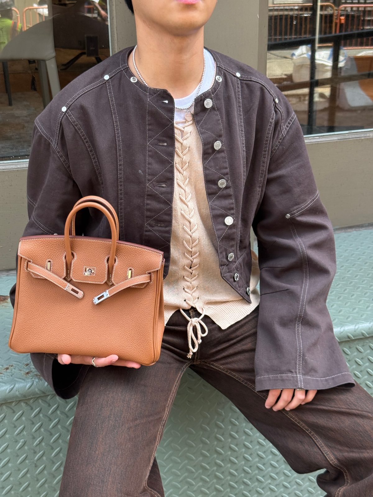 classic tan leather Hermès Birkin bag that he sourced from Japan, paired with a brown button-front jacket over a lace-up cream top.