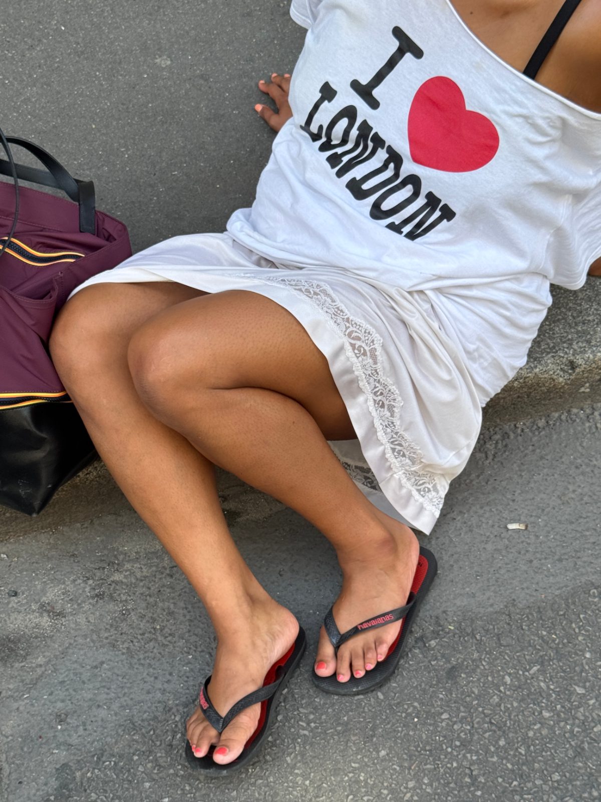White "I heart London" top, white lace slip, black Havaianas flip-flops, and maroon bag.