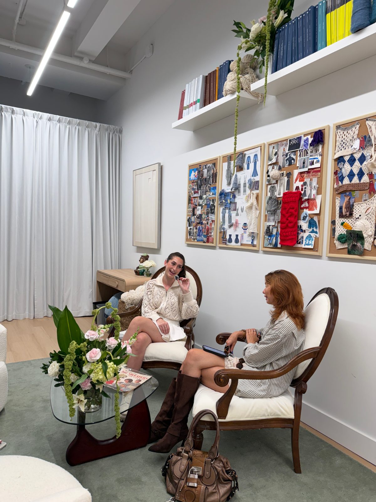 Two women in an office, one in a cream knit sweater, the other in a striped shirt.