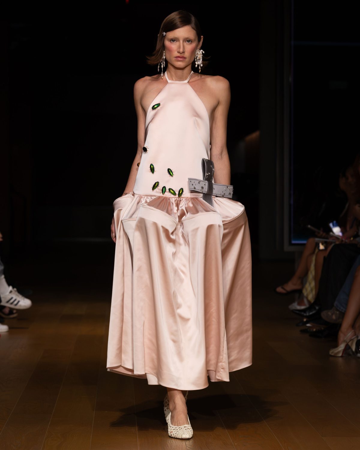Pink halter dress with green beetle embellishments, grey bow belt, and white woven shoes.