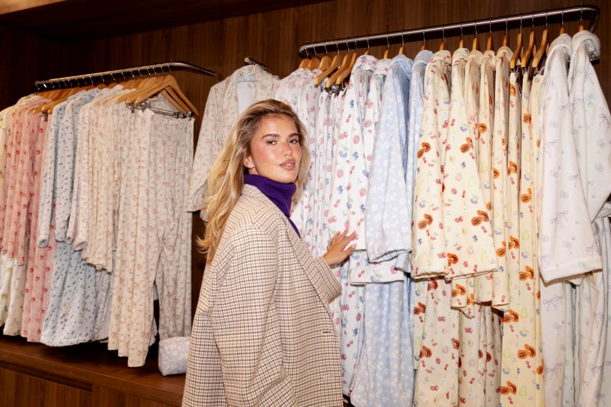 Brown plaid blazer over purple turtleneck, next to racks of pastel patterned loungewear.