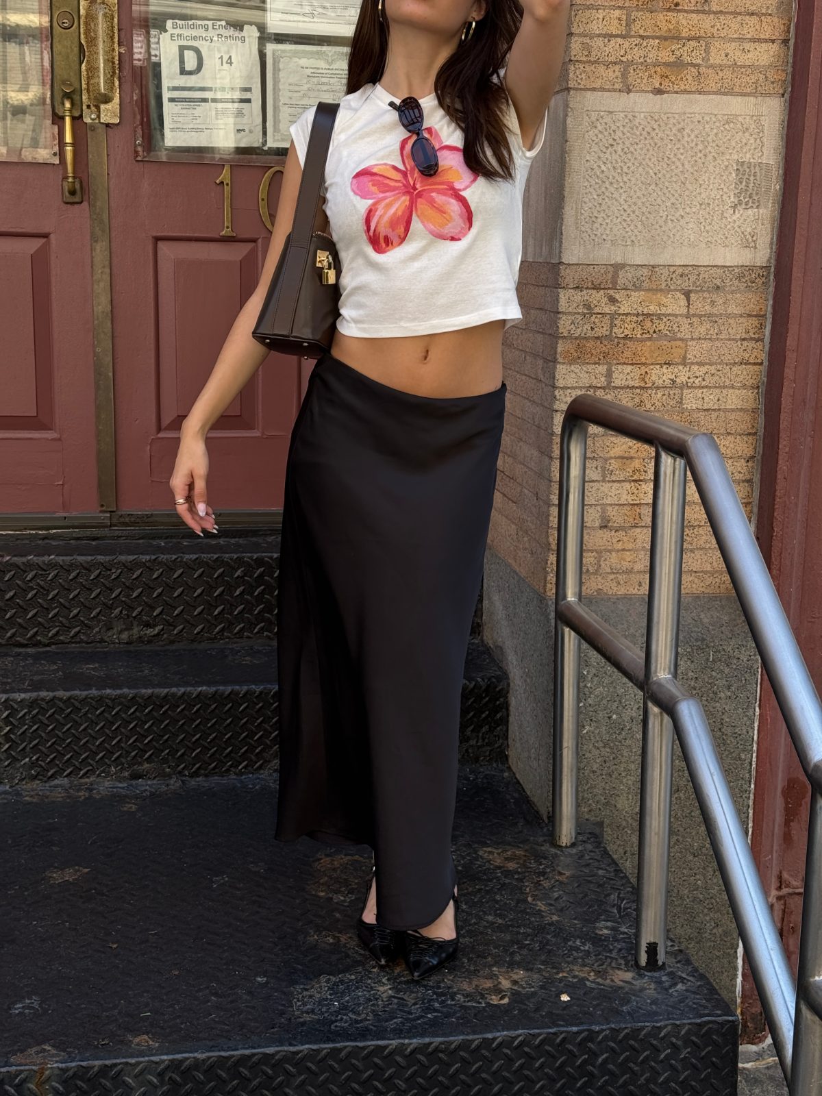 White crop top with pink flower print, black maxi skirt, and pointed-toe heels.