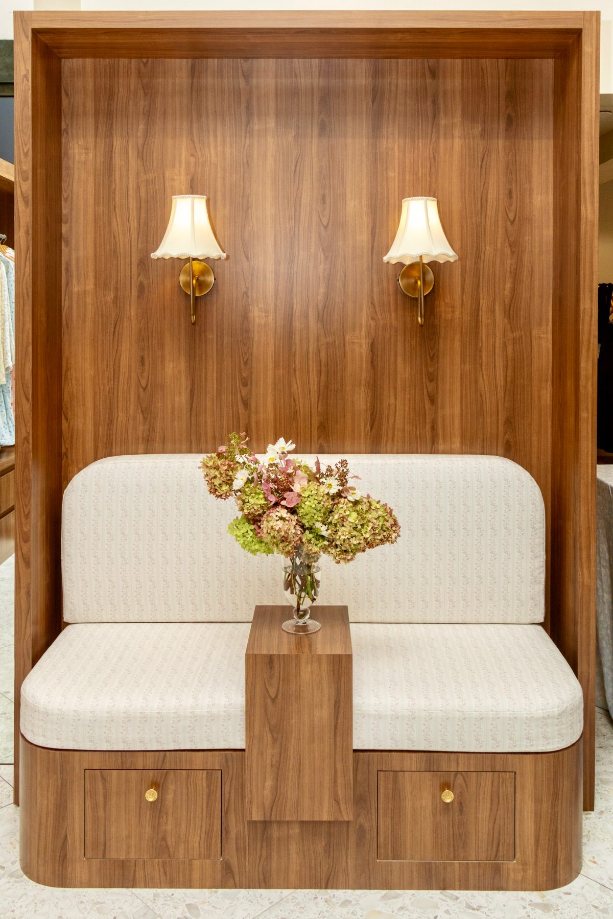 Wooden booth seating with patterned cushions, wall sconces, and a flower vase.