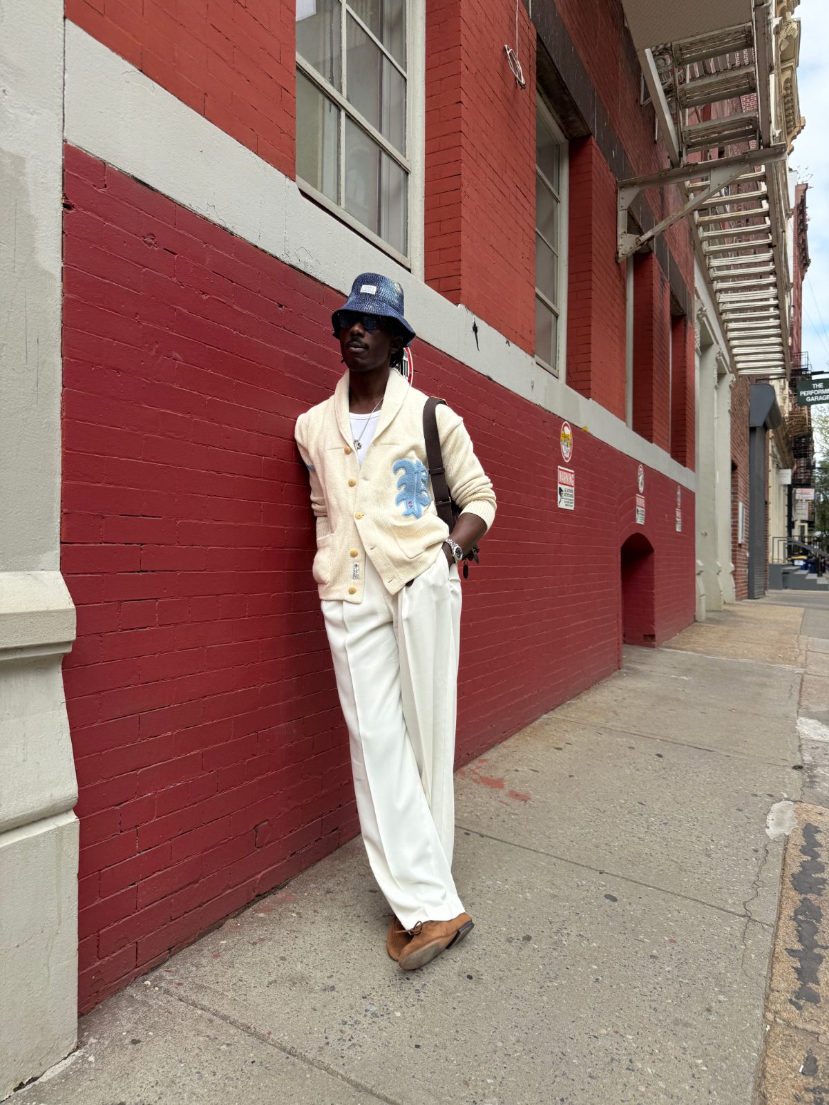 pleated white wide-leg trousers with an ivory shawl-collar cardigan, complete with blue graphic detailing and brown loafers.