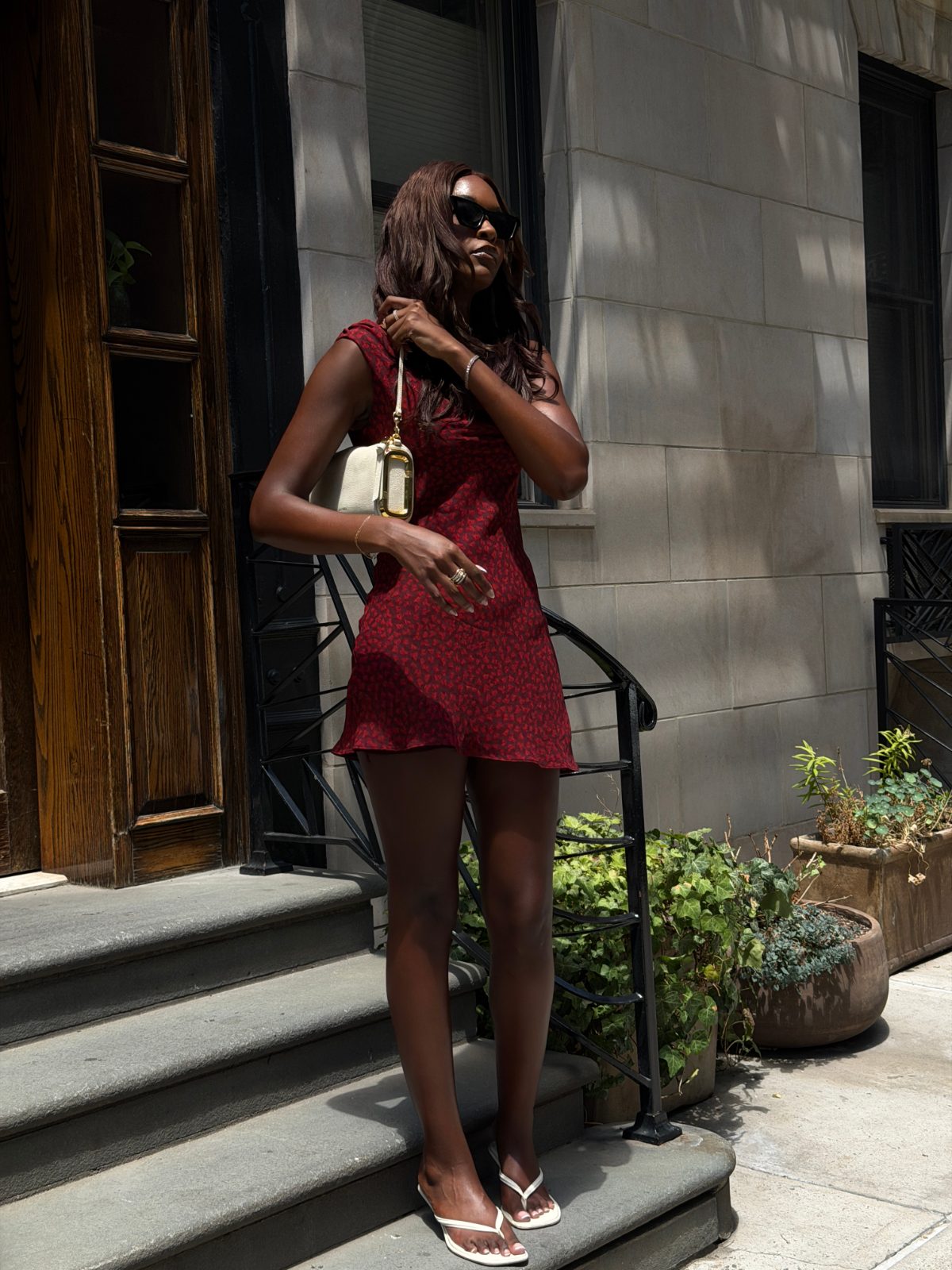 Red floral mini dress with white heeled thong sandals and a small white handbag.