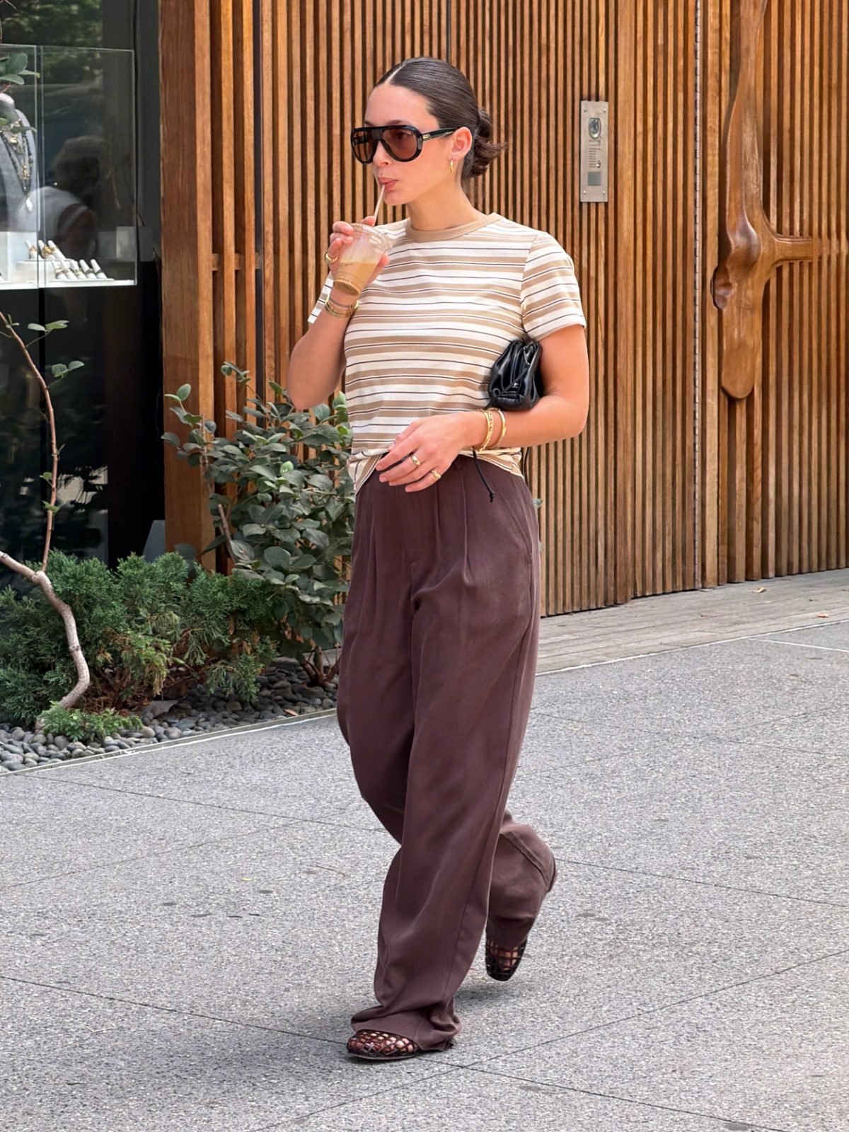 Beige striped tee, brown wide-leg pants, black woven flats, and a black clutch.