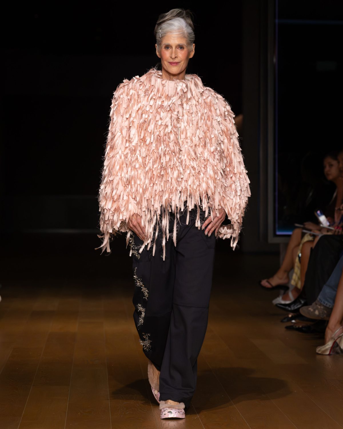 Pink textured top with long black embellished pants and pink fluffy shoes.