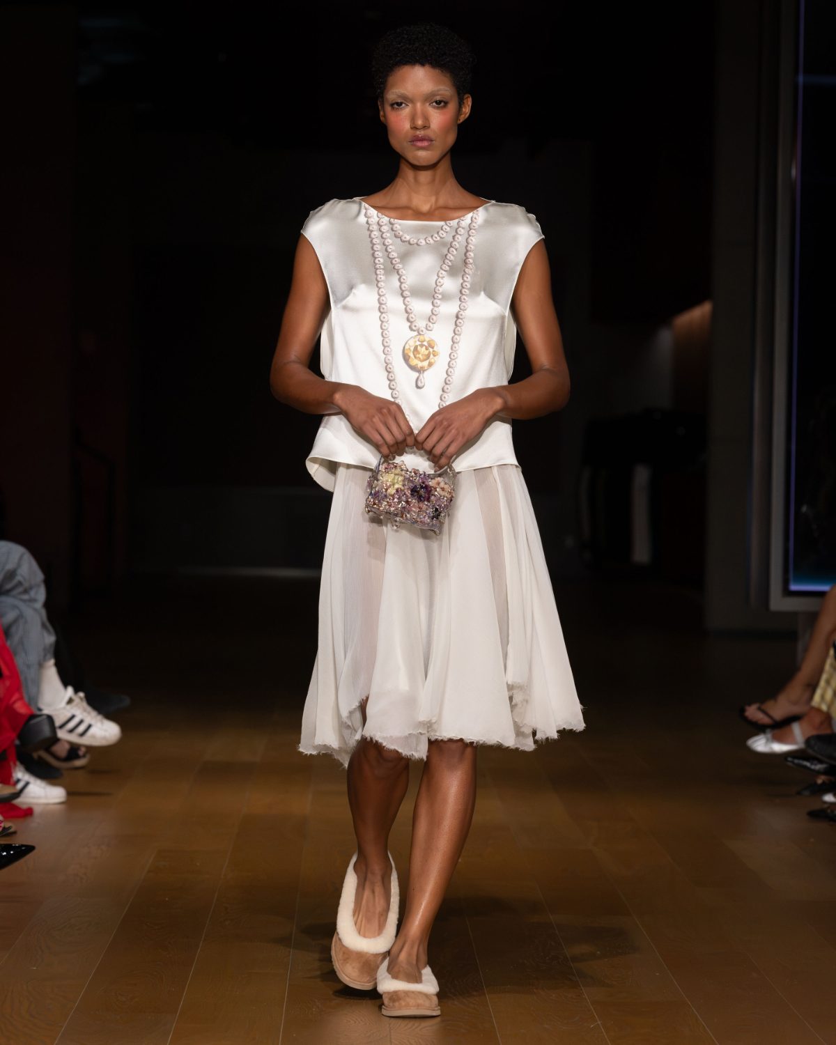 White satin top with sheer skirt, long beaded necklace, colorful embellished bag, and fuzzy mules.