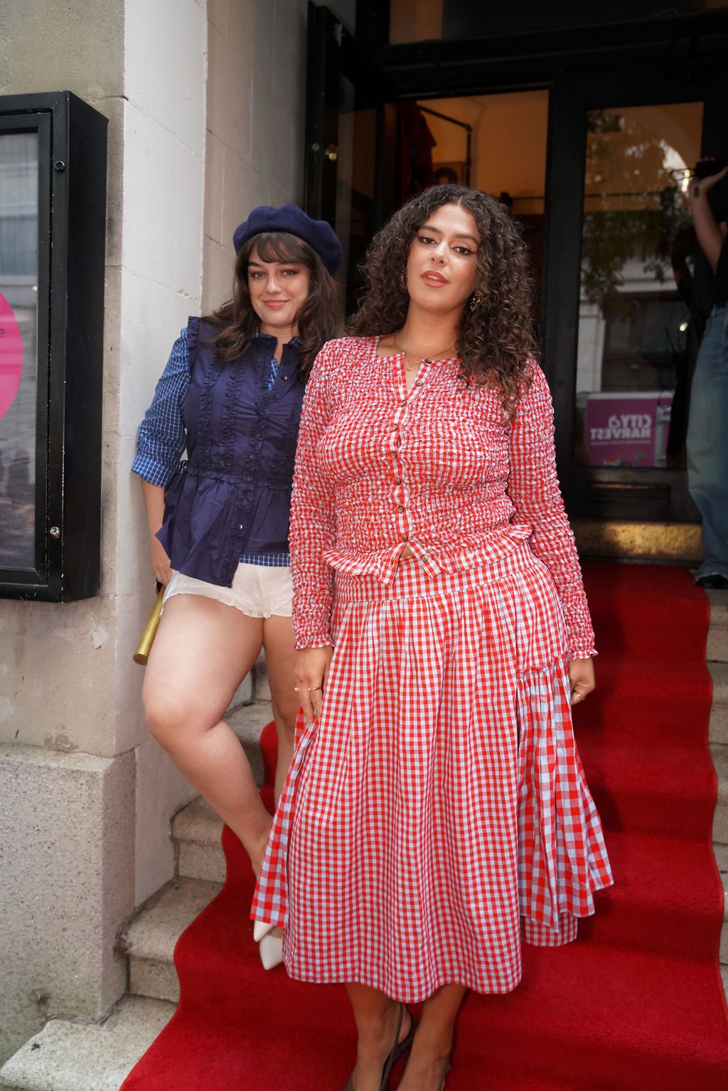 Red and white gingham shirred top and skirt, navy vest, white shorts, and beret on red carpet.