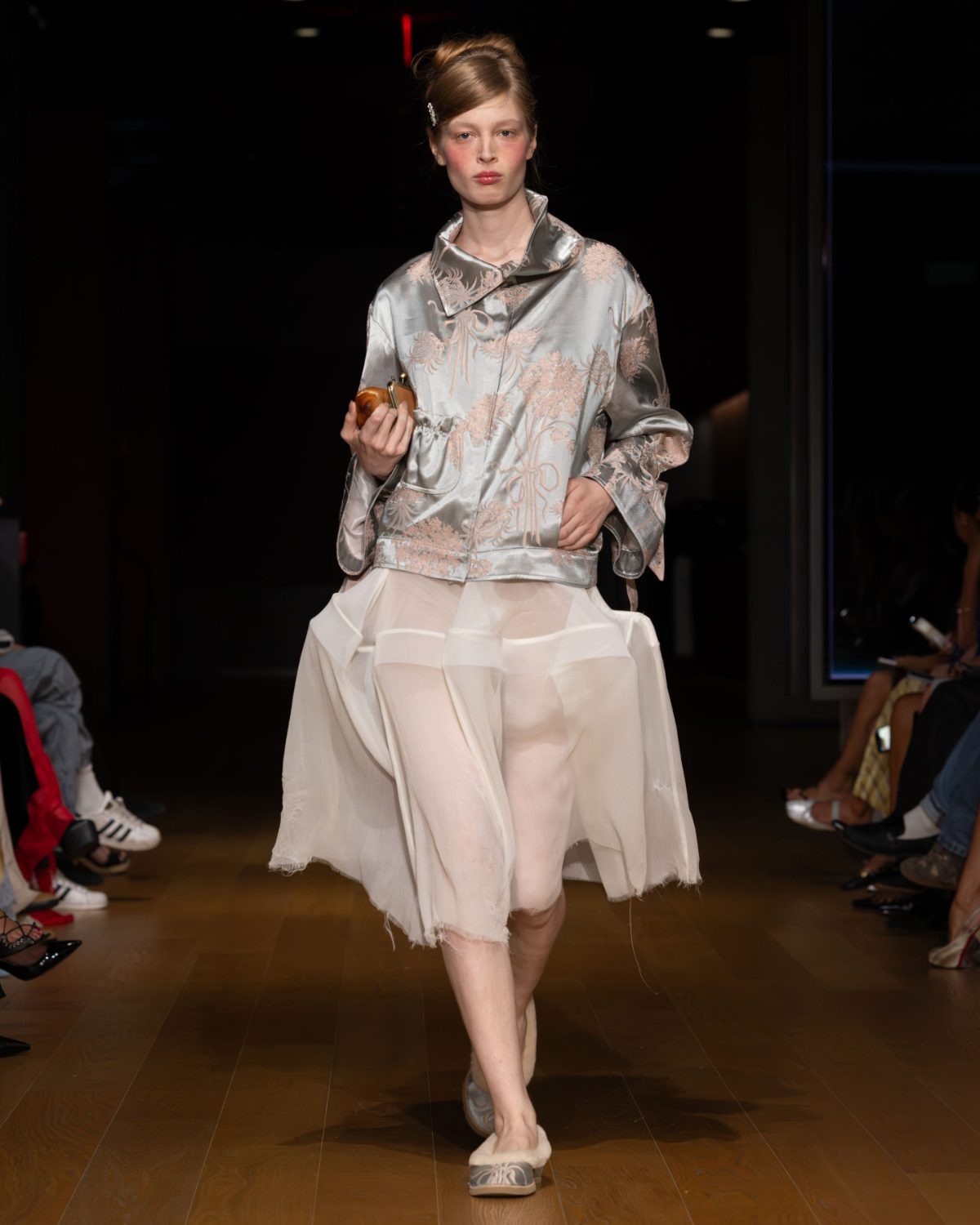 Light grey embroidered jacket with white sheer layered skirt and fluffy grey shoes.