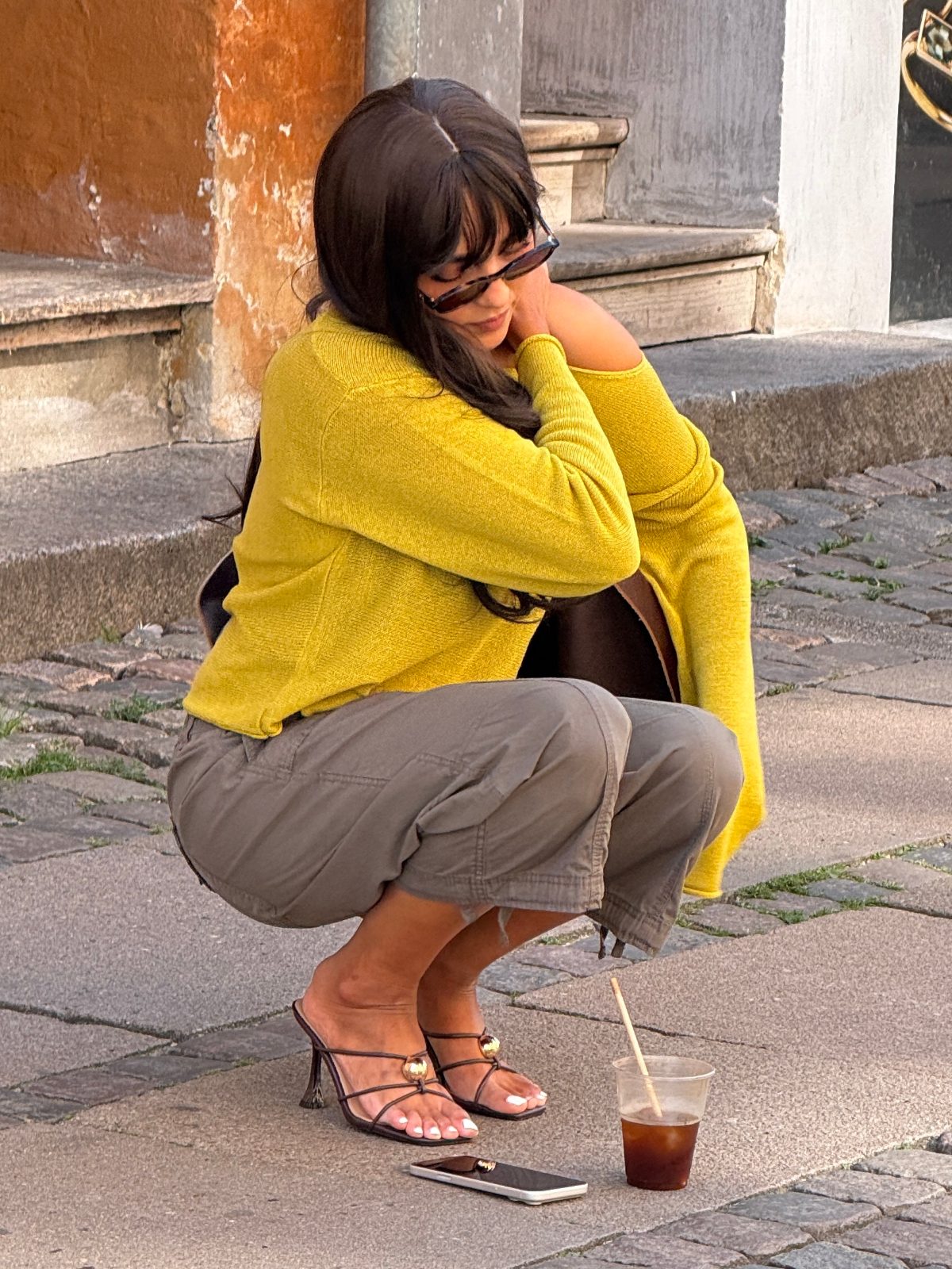 Yellow knit sweater, olive cargo pants, and black heels with gold accents.