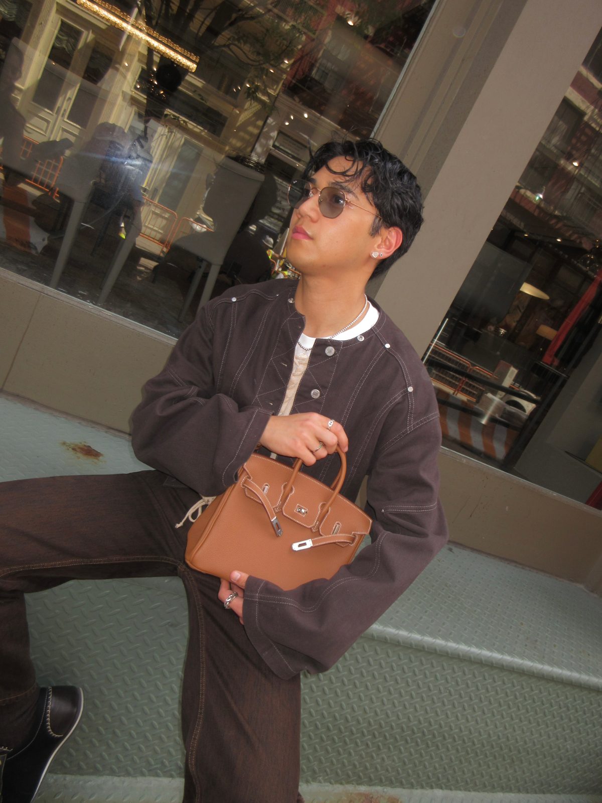 classic tan leather Hermès Birkin bag that he sourced from Japan, paired with a brown button-front jacket over a lace-up cream top.