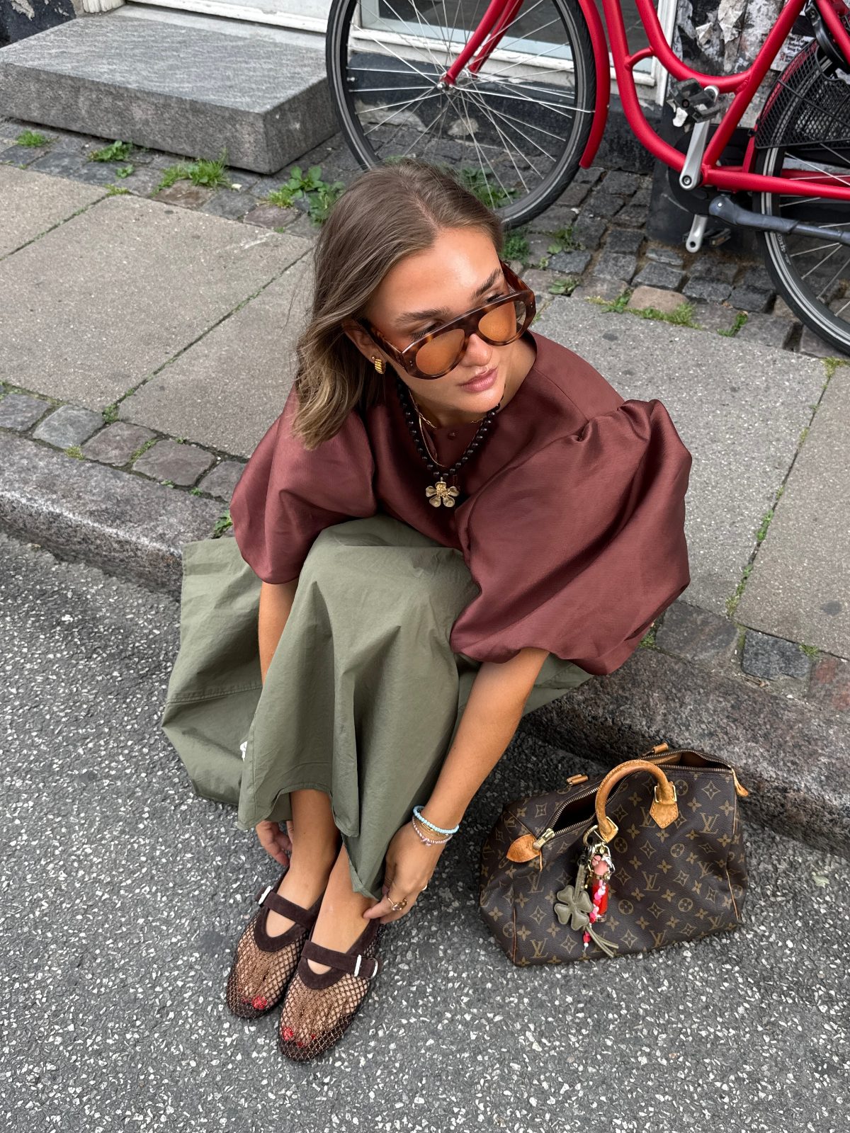 Brown puff-sleeve top, olive skirt, mesh flats, and Louis Vuitton bag on a street.