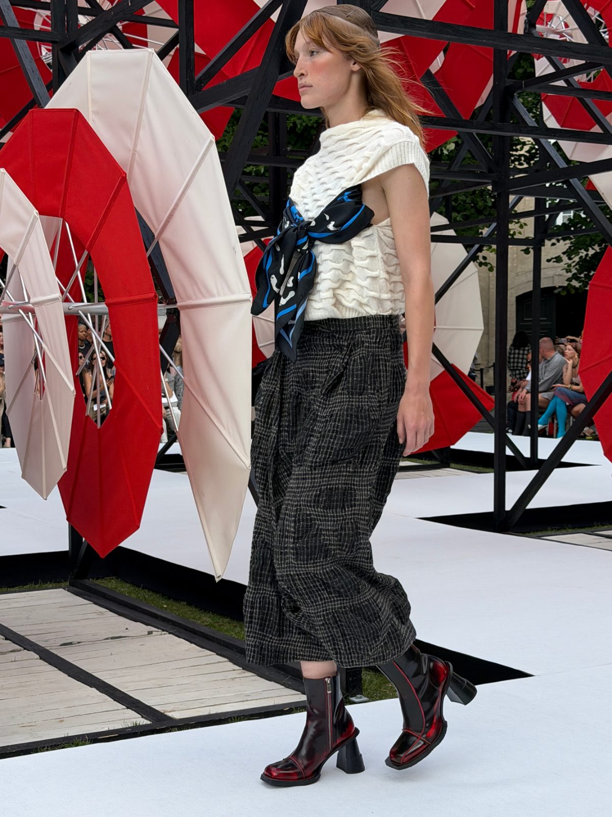 White textured sleeveless top, plaid pants, patterned black scarf, and red ombre boots.