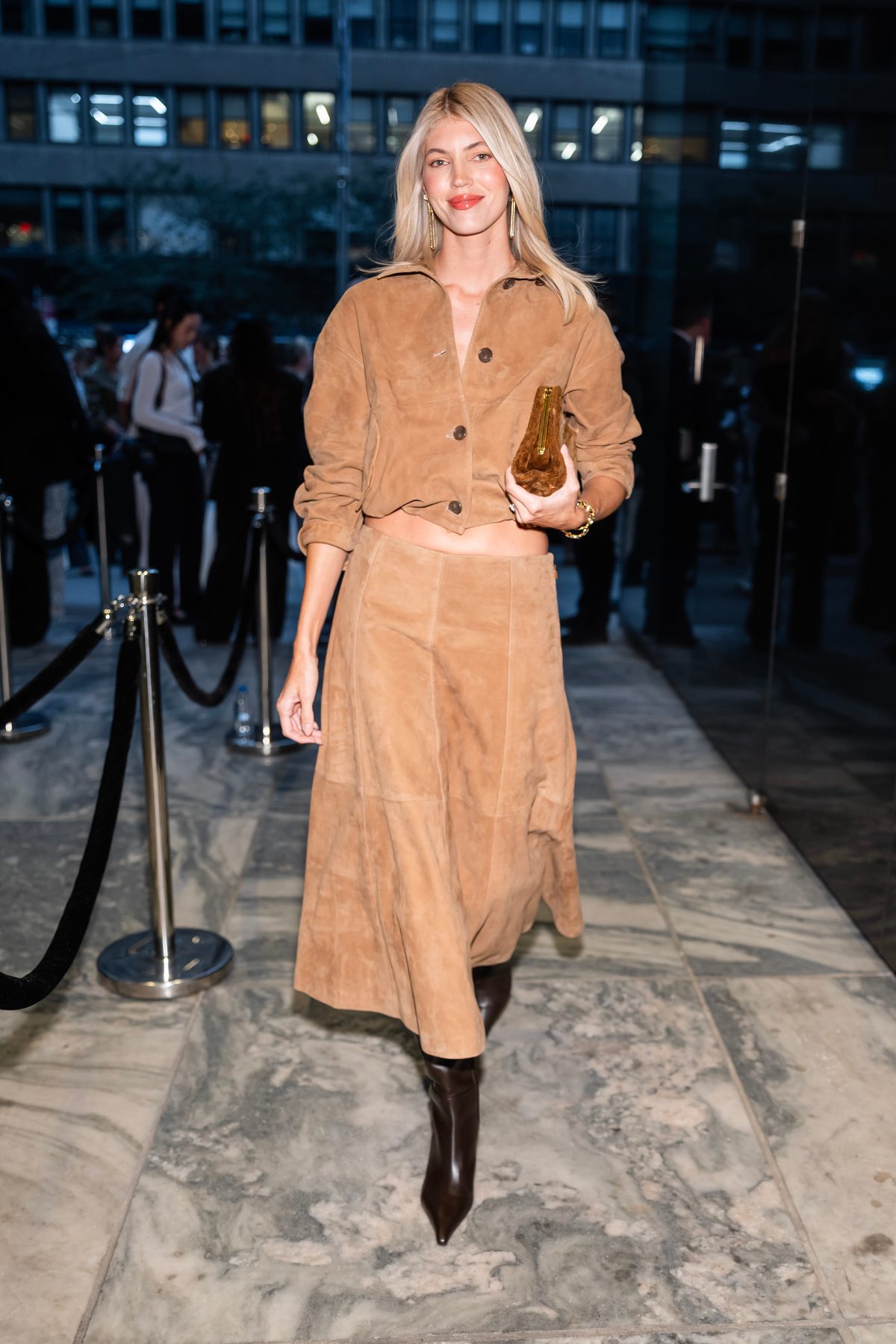 Brown suede cropped jacket and midi skirt, dark brown boots, and gold clutch.