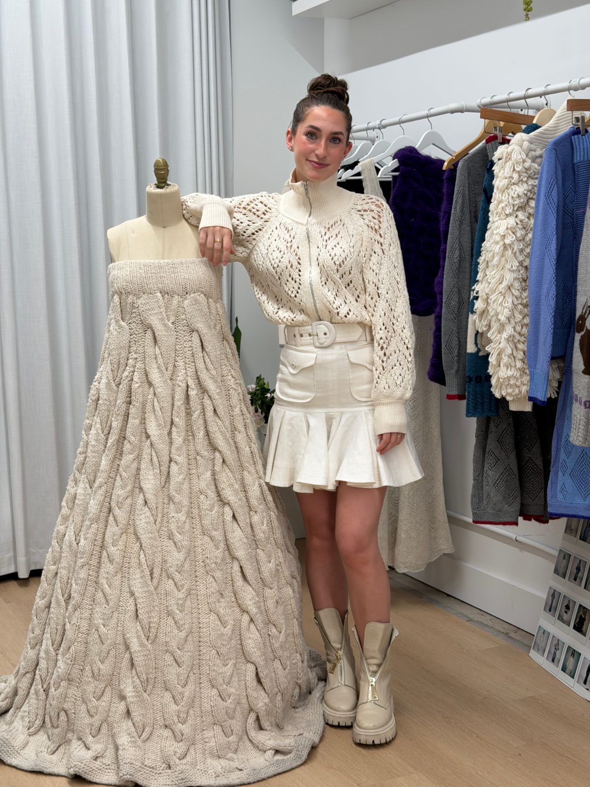 Cream open-knit zippered jacket, white mini skirt with belt, beige combat boots, next to a knit dress.