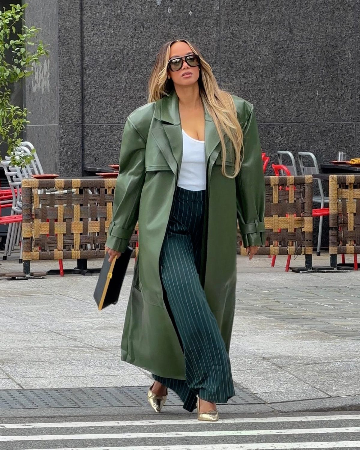 Olive green oversized trench coat with pinstripe pants and gold heels.