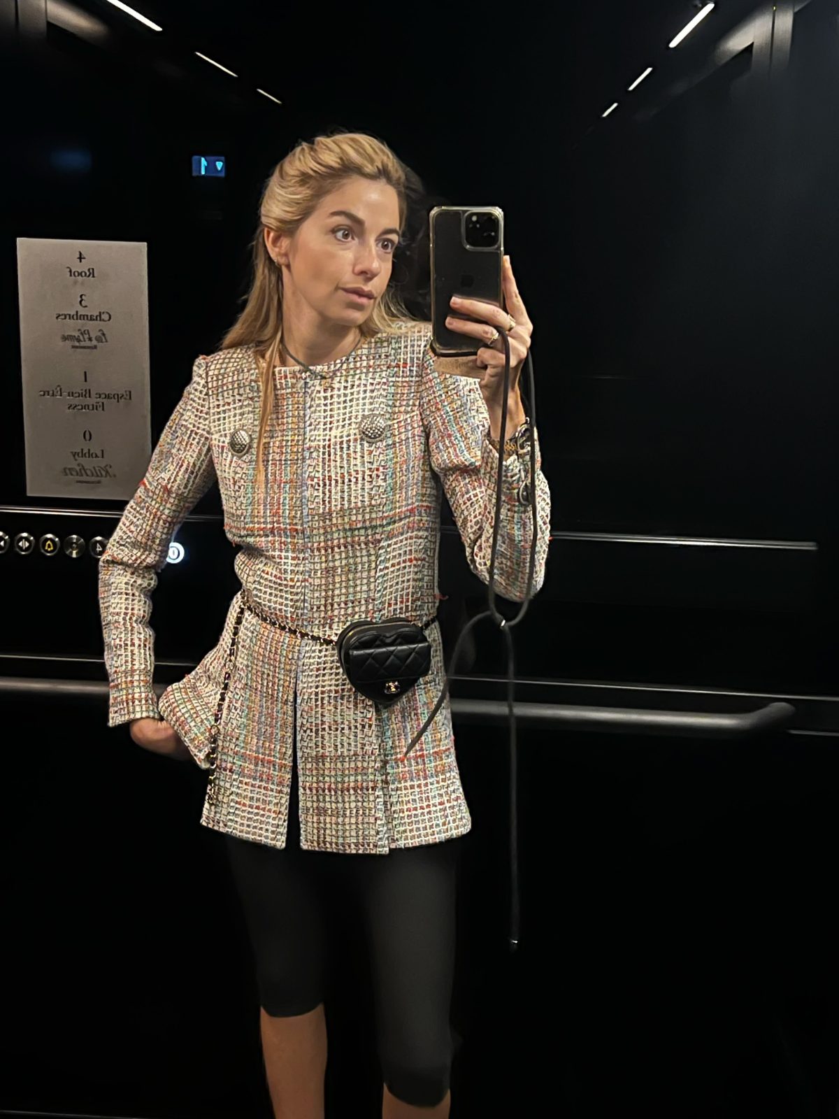Colorful tweed blazer with black biker shorts and a quilted heart-shaped fanny pack.