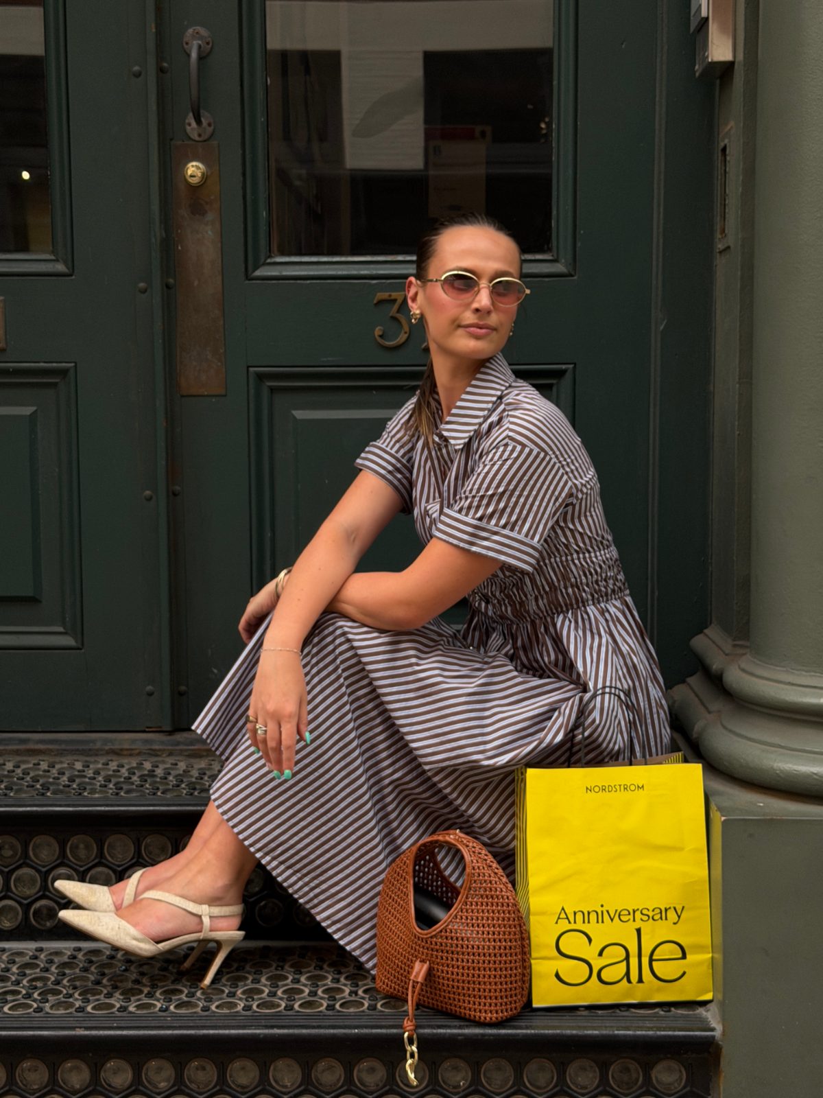 Brown and white striped midi dress, slingback heels, woven bag, and sunglasses, with a sale bag.