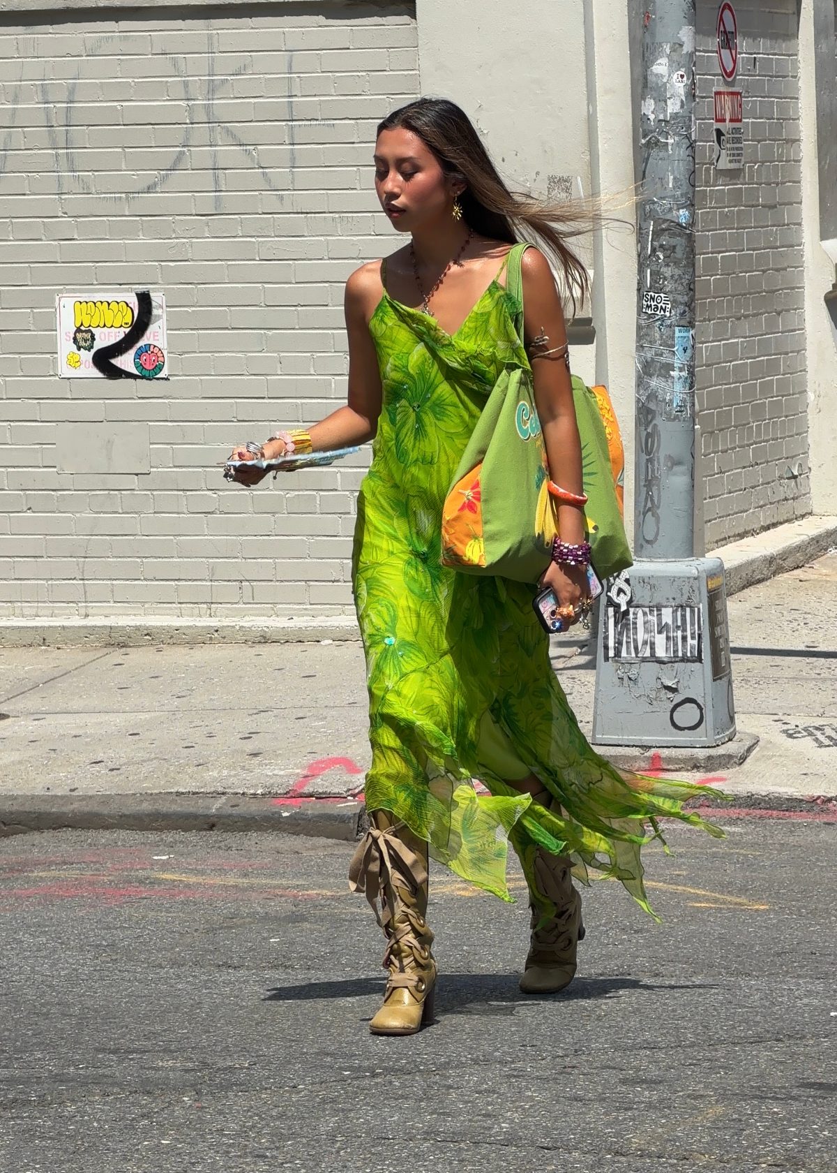 Green floral slip dress with tan lace-up boots and a green tote bag on a city street.