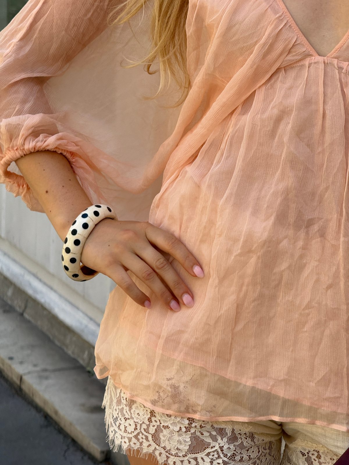 Peach blouse with lace shorts and a black and white polka dot bracelet.