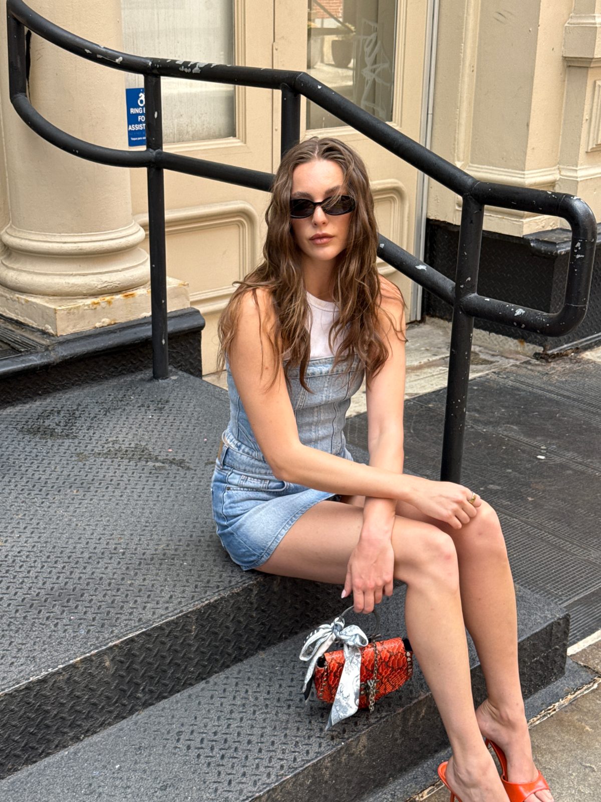 Denim mini dress with white crop top, black sunglasses, and orange mules.