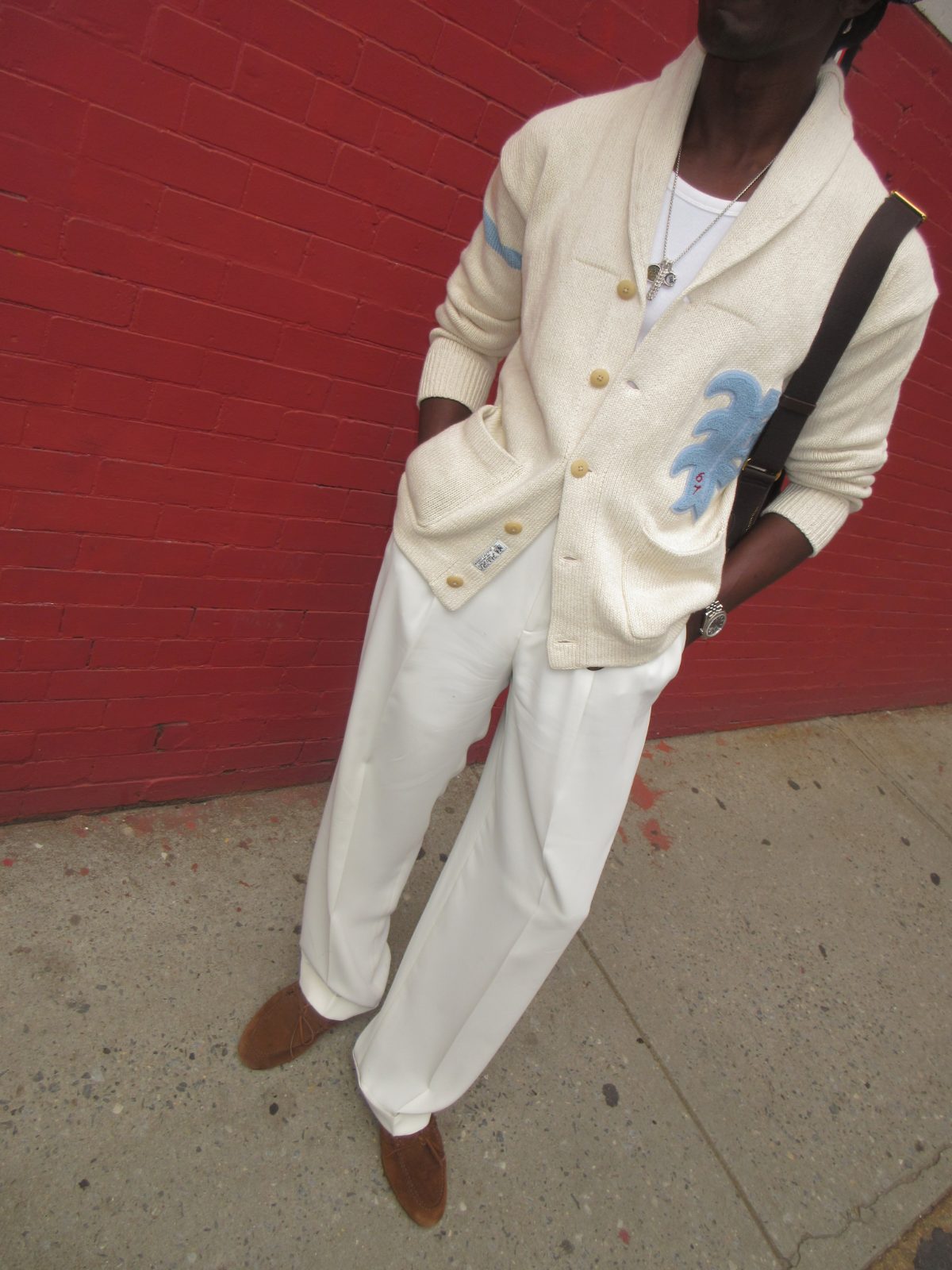 pleated white wide-leg trousers with an ivory shawl-collar cardigan, complete with blue graphic detailing and brown loafers.
