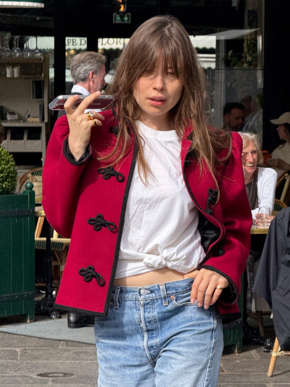 Red military-style jacket with black trim over a knotted white tee and light-wash jeans.