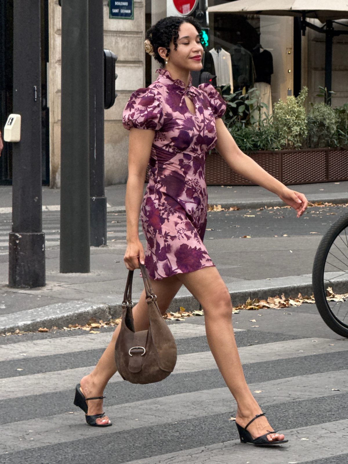 Purple floral print mini dress with puff sleeves, brown shoulder bag, and black wedge sandals.