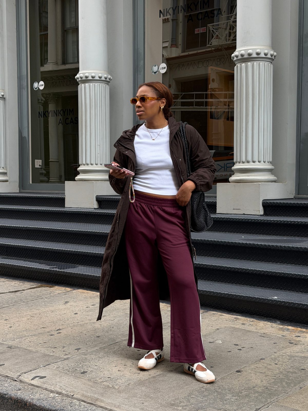 Brown trench coat, white ribbed crop top, burgundy track pants, and Mary Jane flats.