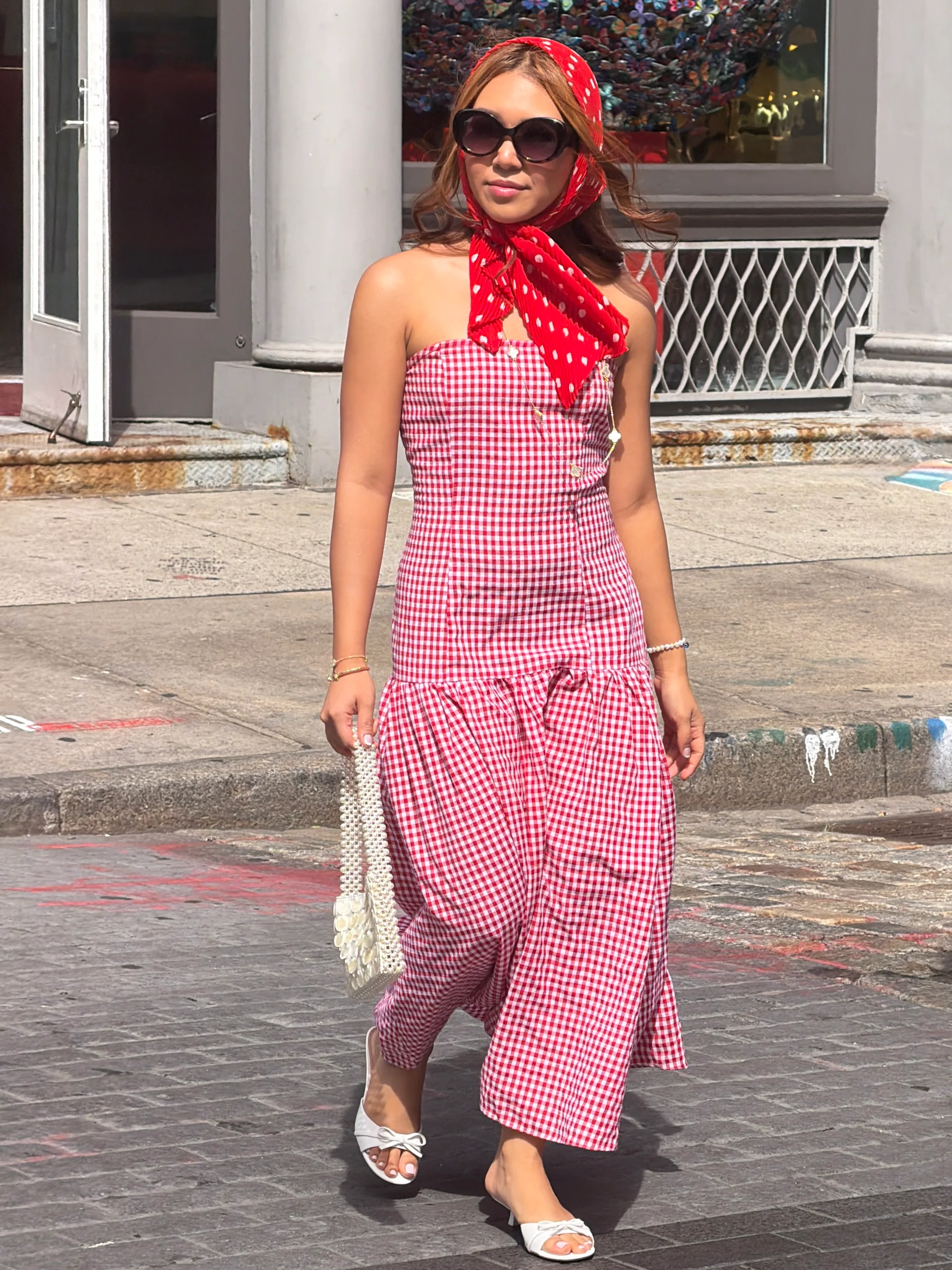 Red gingham strapless maxi dress, red polka dot scarf, white pearl bag, and white mules.
