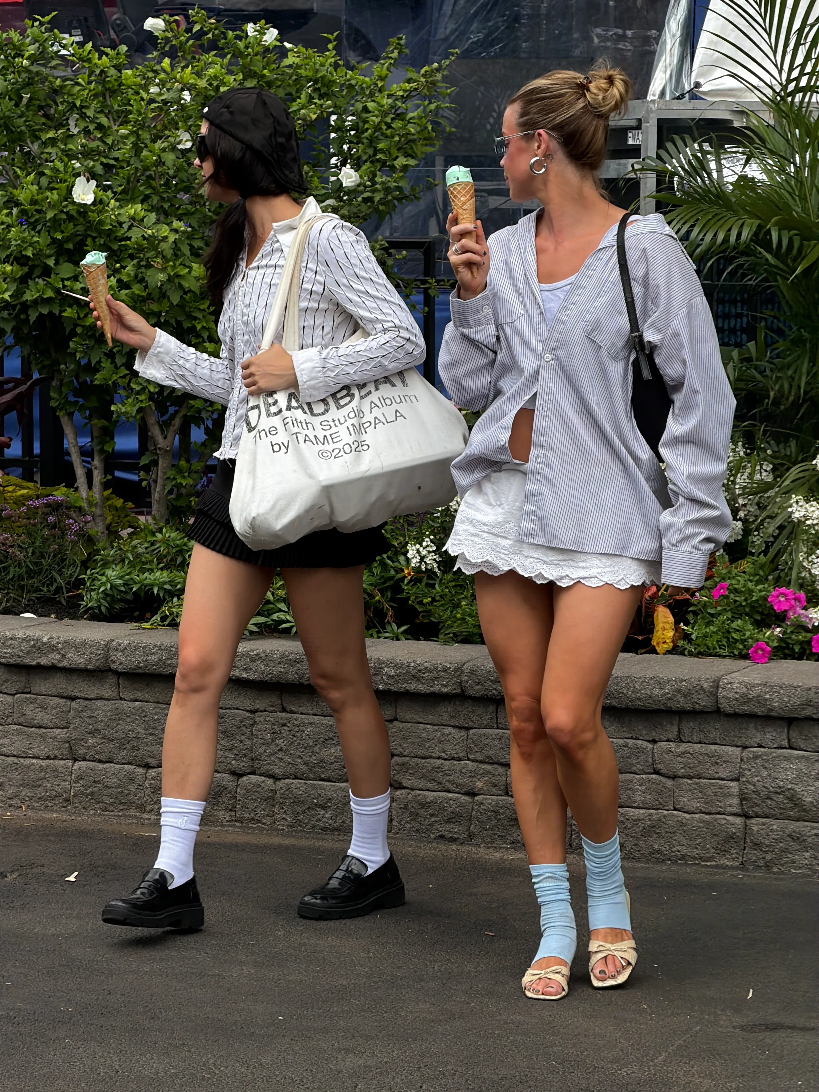 Summer street style: Two women in button-down shirts, shorts, and sandals, holding ice cream.