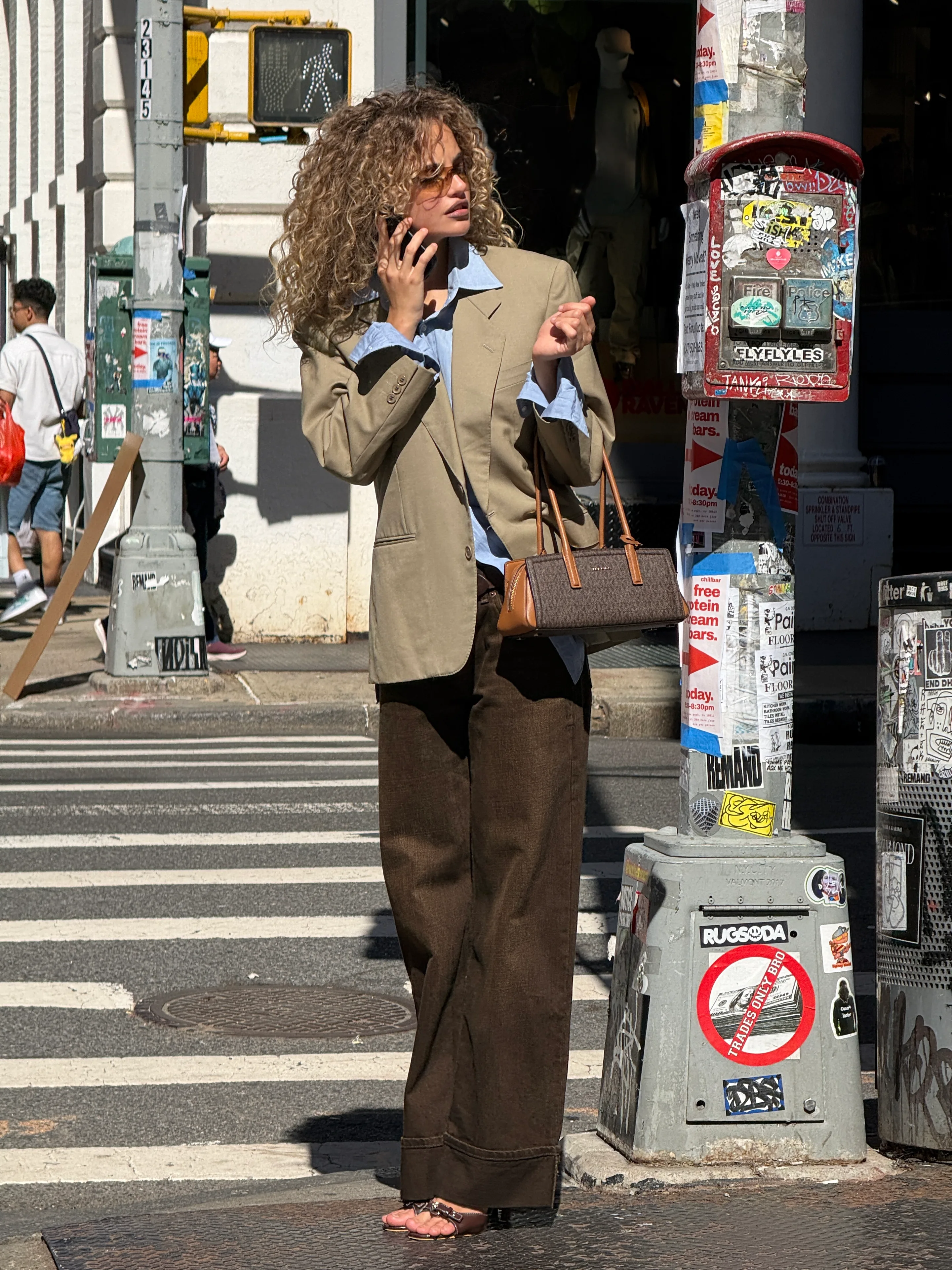 Khaki blazer, light blue shirt, brown wide-leg pants, and brown sandals in a city street.