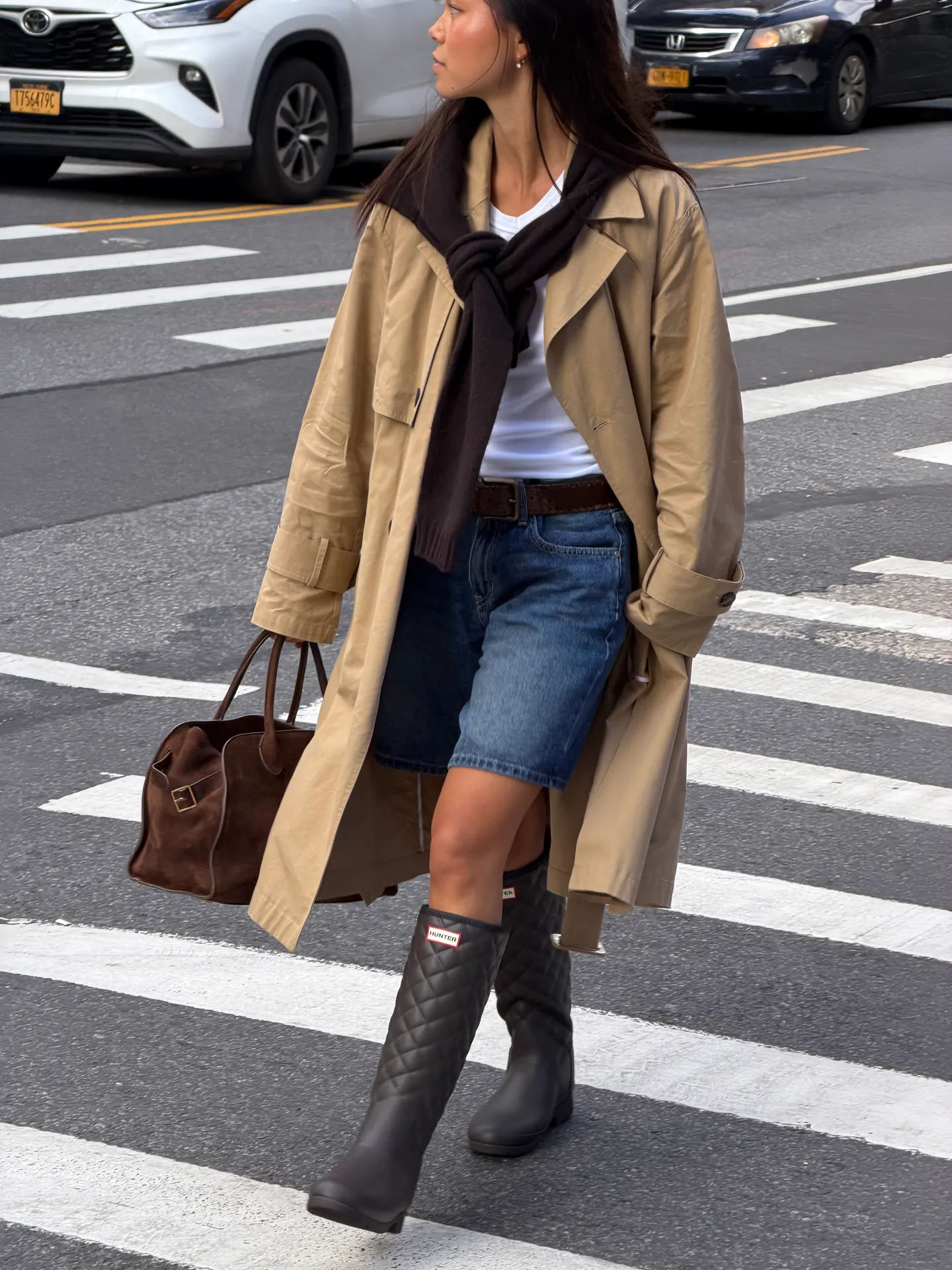 Tan trench coat, white tee, denim shorts, black quilted Hunter boots, brown suede bag.