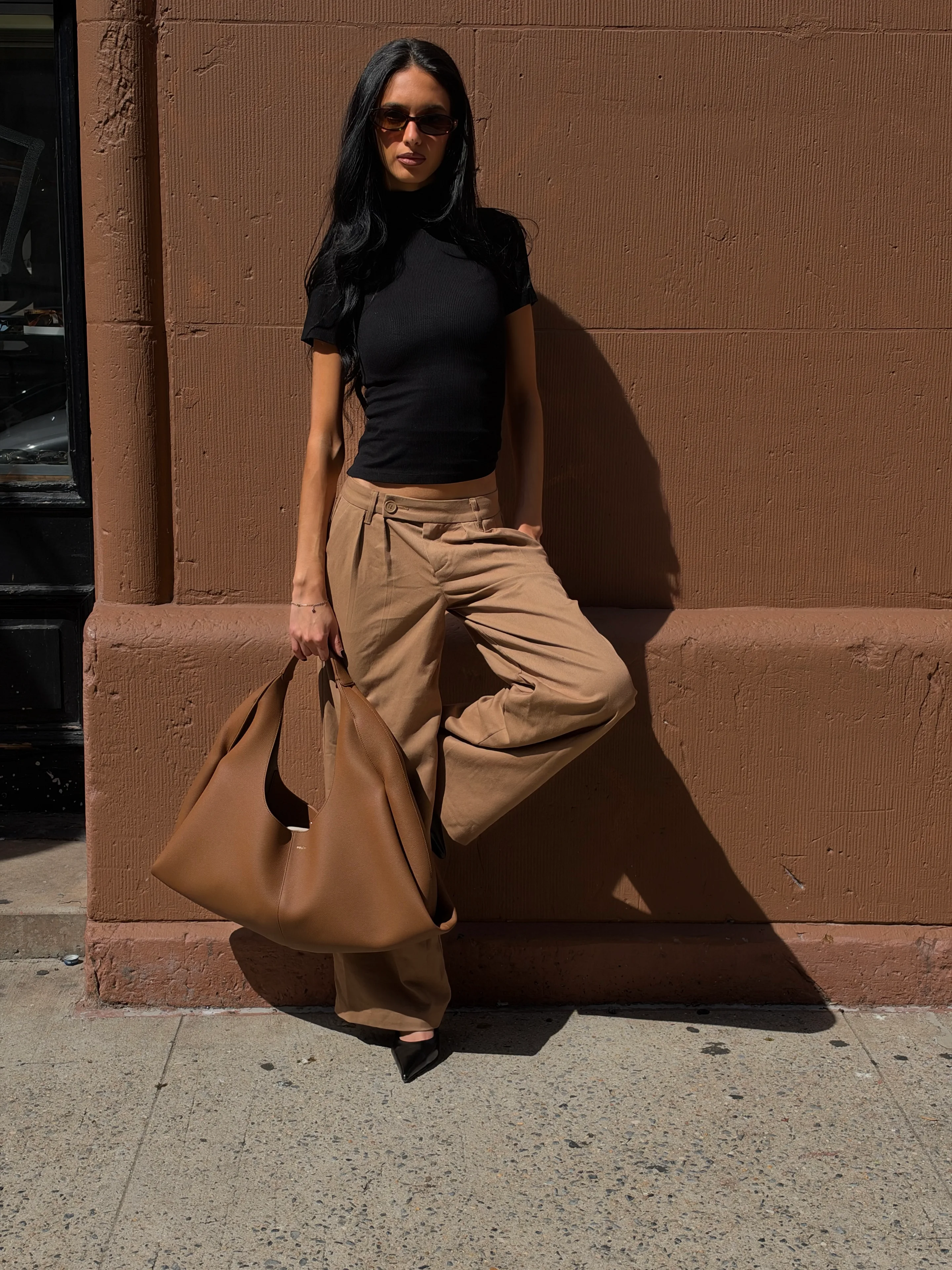 Black ribbed turtleneck top, wide-leg khaki pants, pointed black heels, and a large brown tote bag.