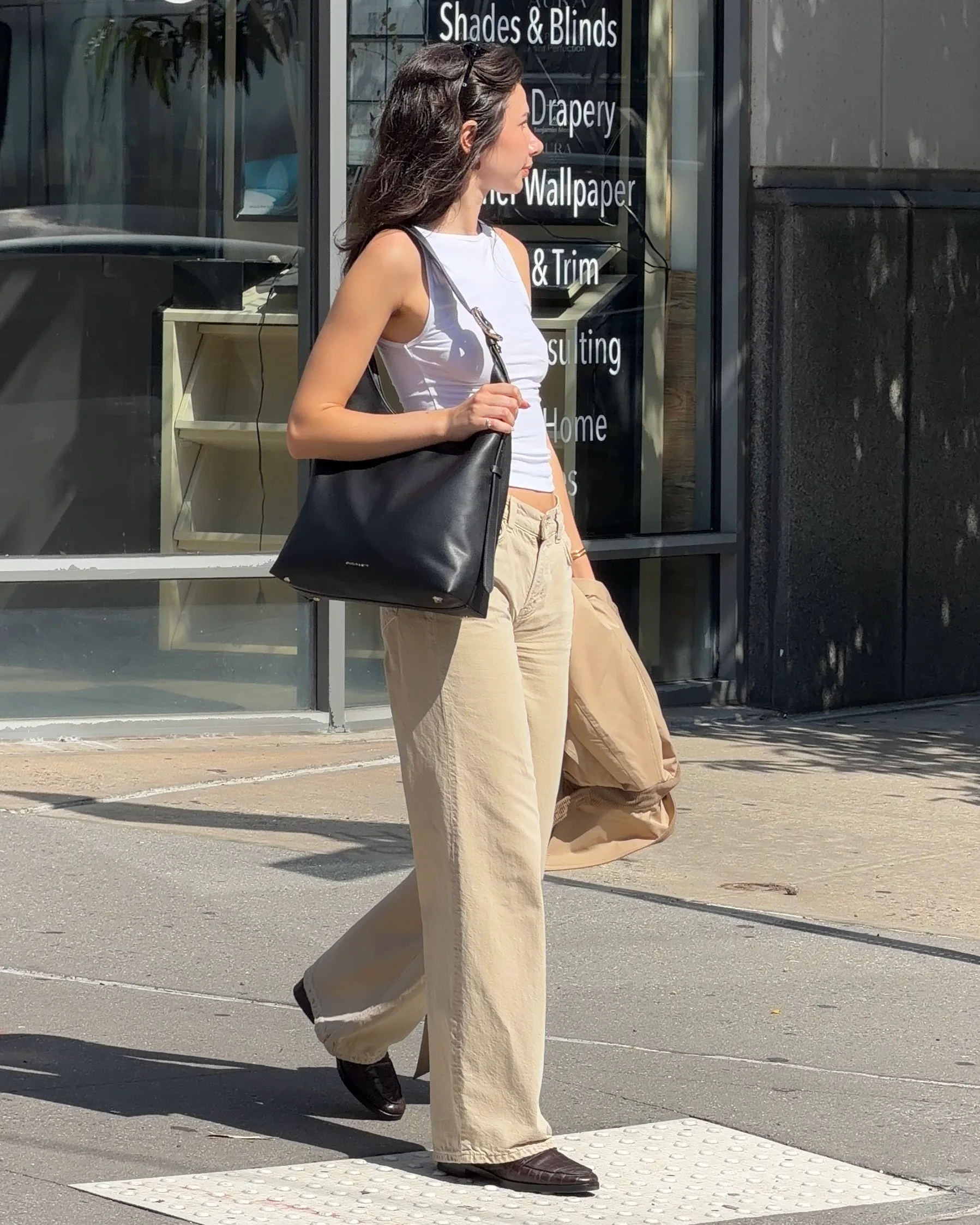 White tank top and khaki wide-leg pants with a black shoulder bag.