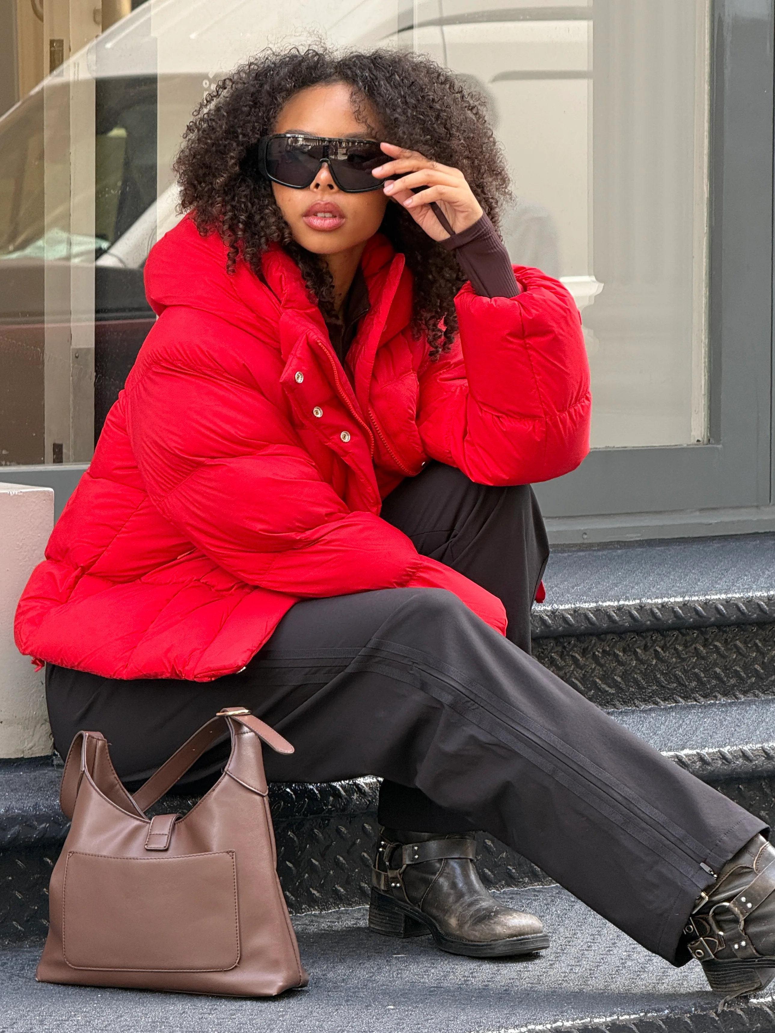 Red puffer jacket with black wide-leg pants, black moto boots, and a brown shoulder bag.