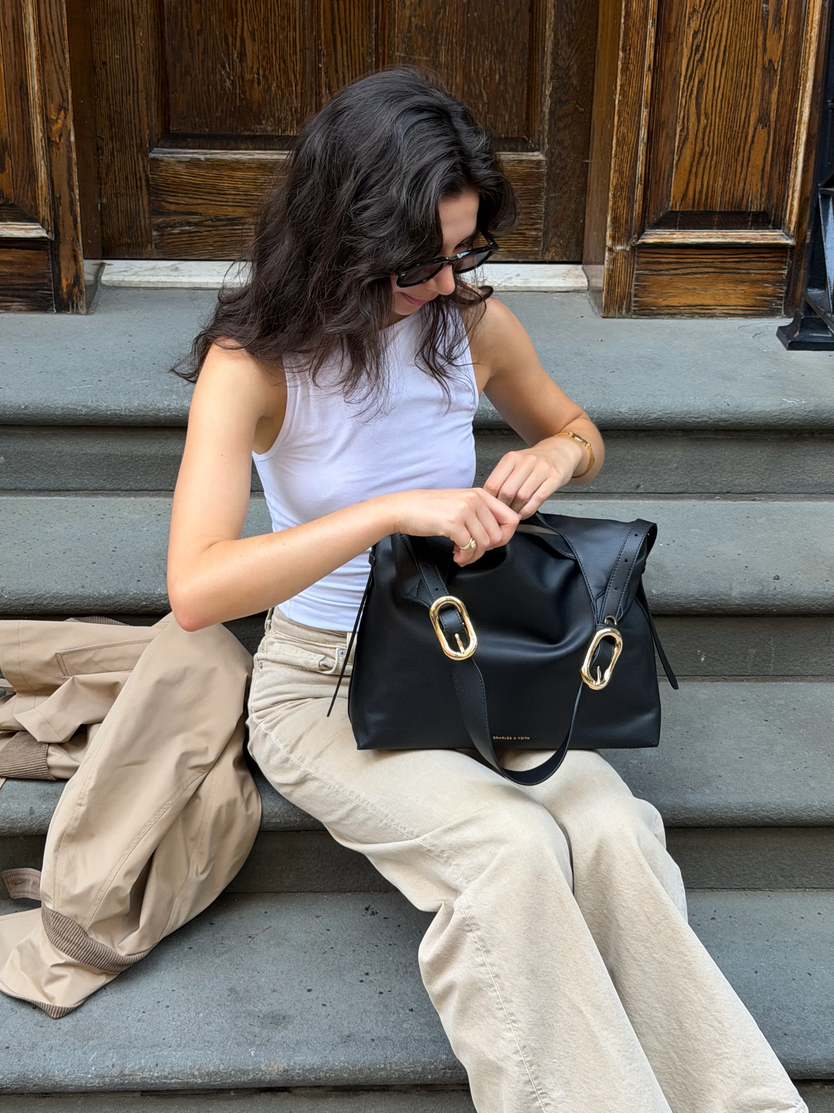 White tank top, beige pants, black crossbody bag with gold hardware.