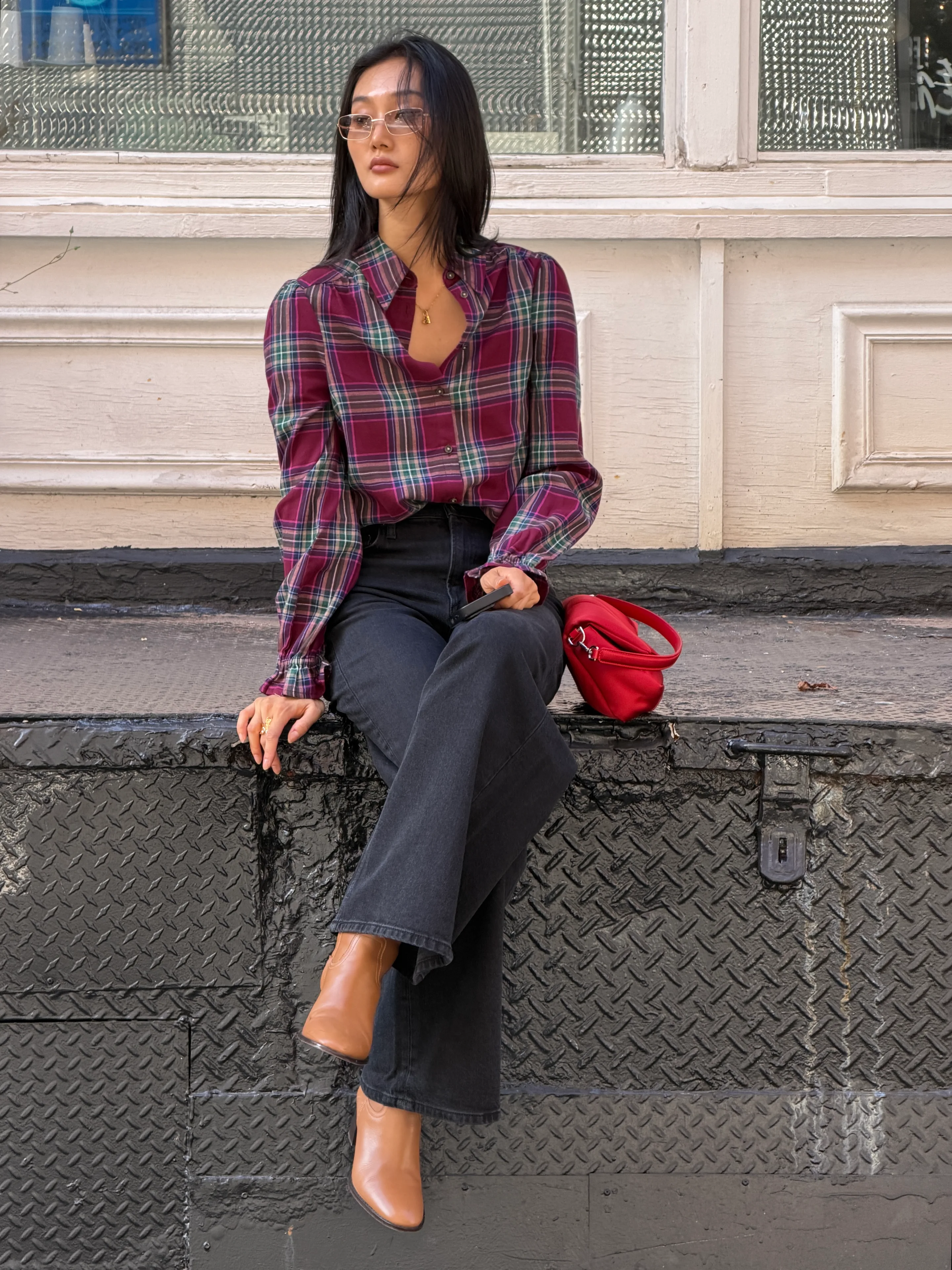 Burgundy plaid blouse with dark jeans, brown ankle boots, and a red bag.