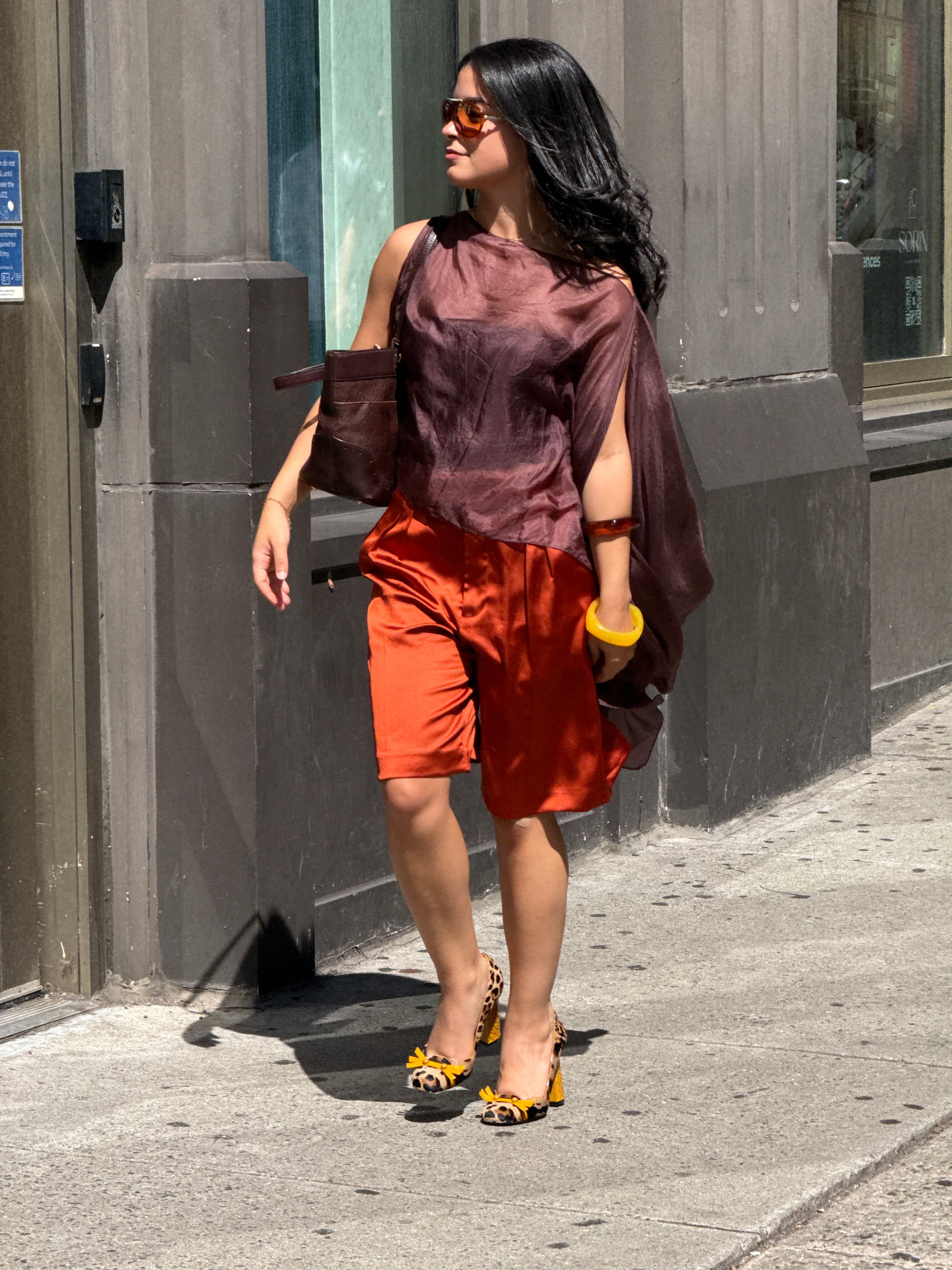 Sheer brown top, orange satin shorts, and leopard print heels with yellow bows.