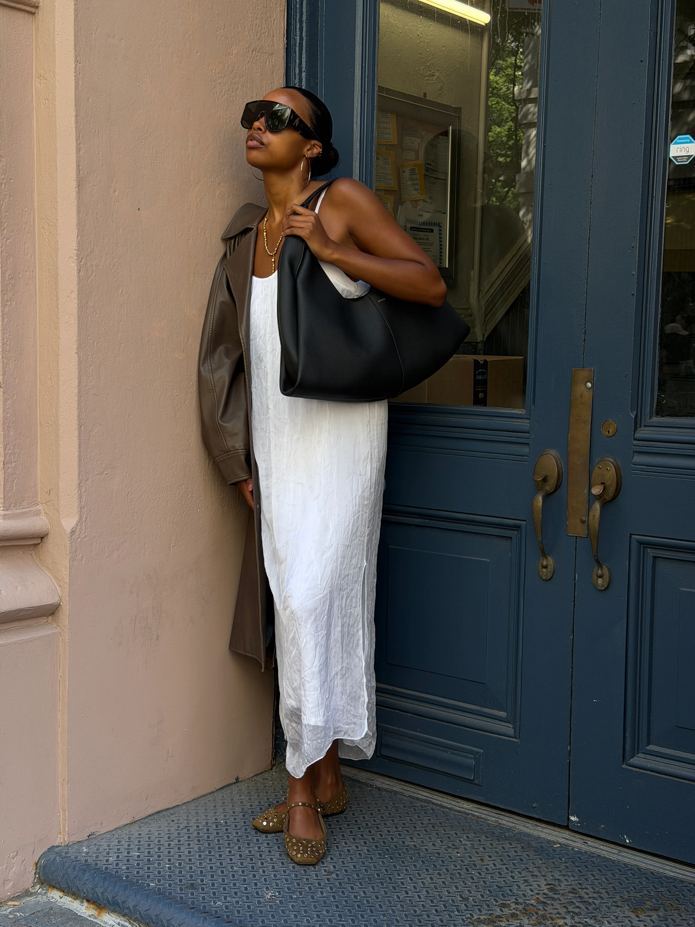 White maxi dress, brown trench coat, studded flats, and oversized sunglasses.