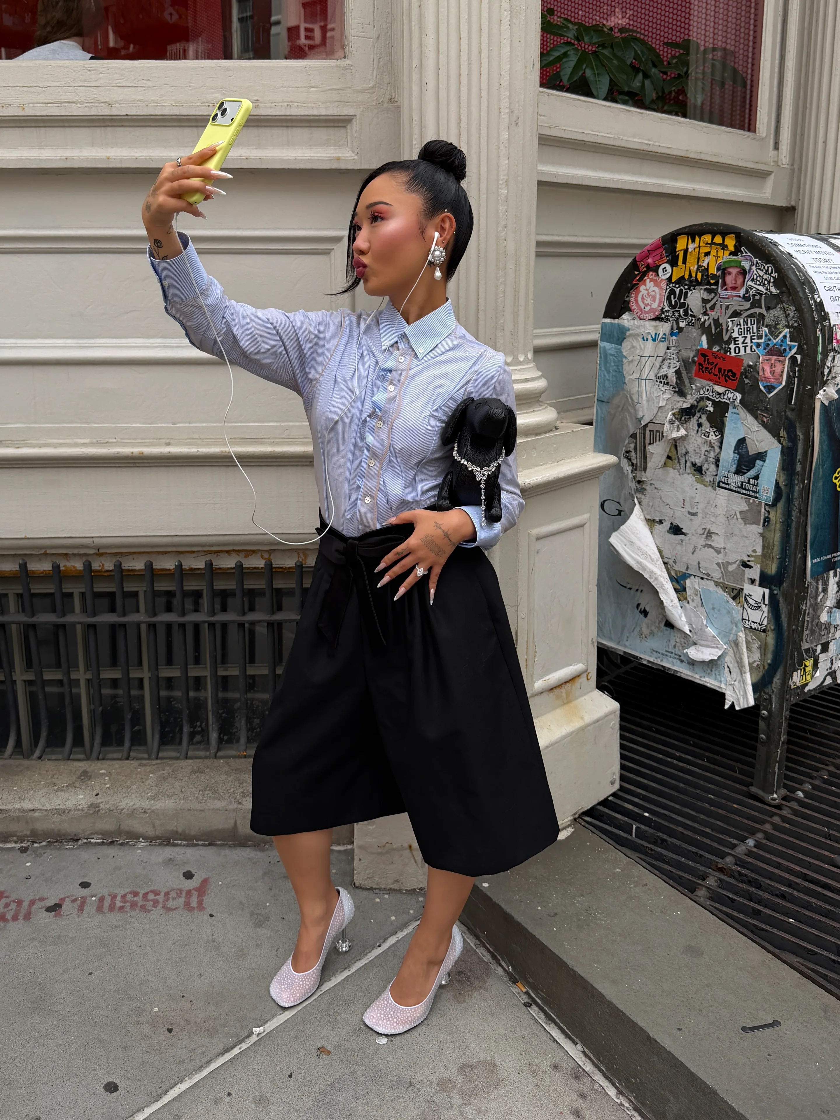 Blue pinstripe button-down shirt, black culottes, studded heels, and a black dog handbag.