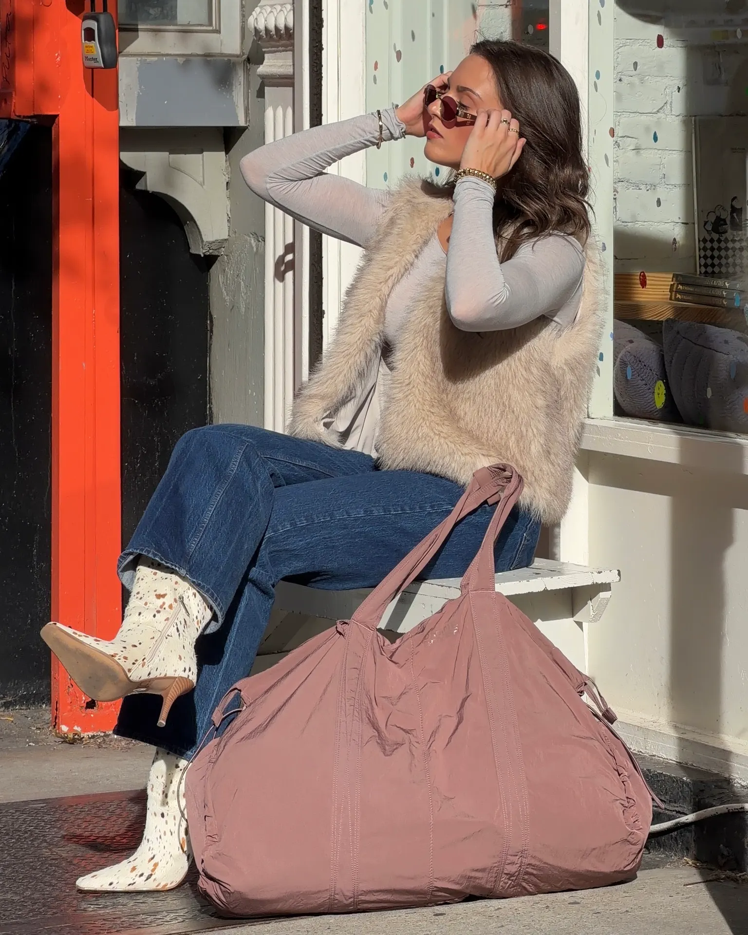 Light grey long-sleeve top, faux fur vest, wide-leg jeans, animal print cowboy boots.