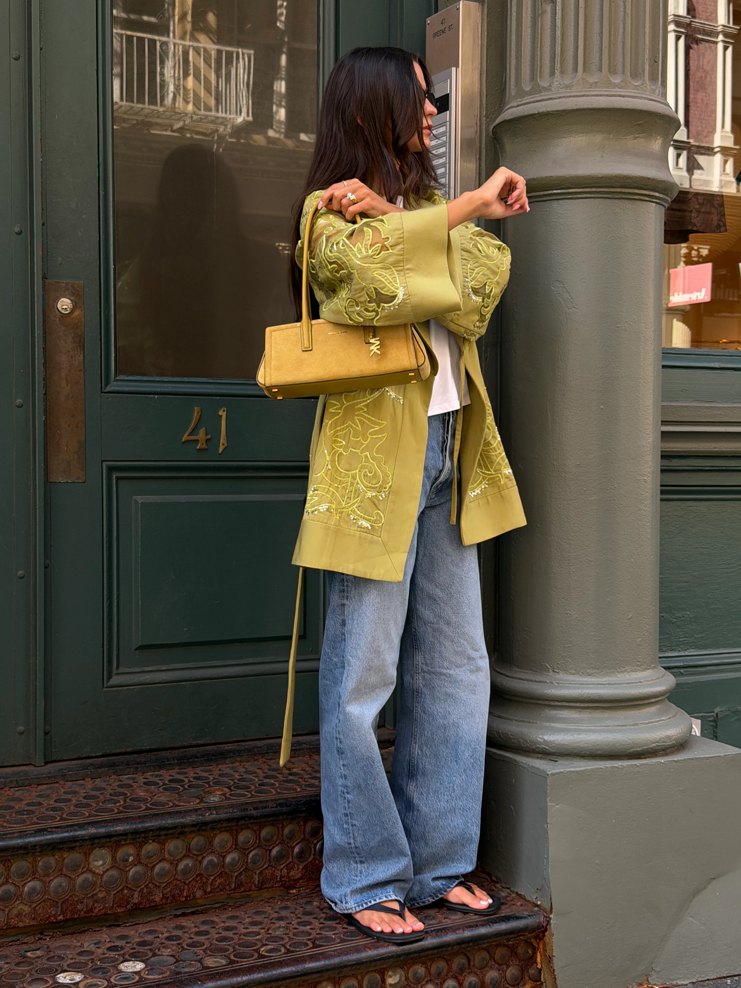 Lime green embroidered kimono, wide-leg jeans, black flip-flops, and a yellow handbag.