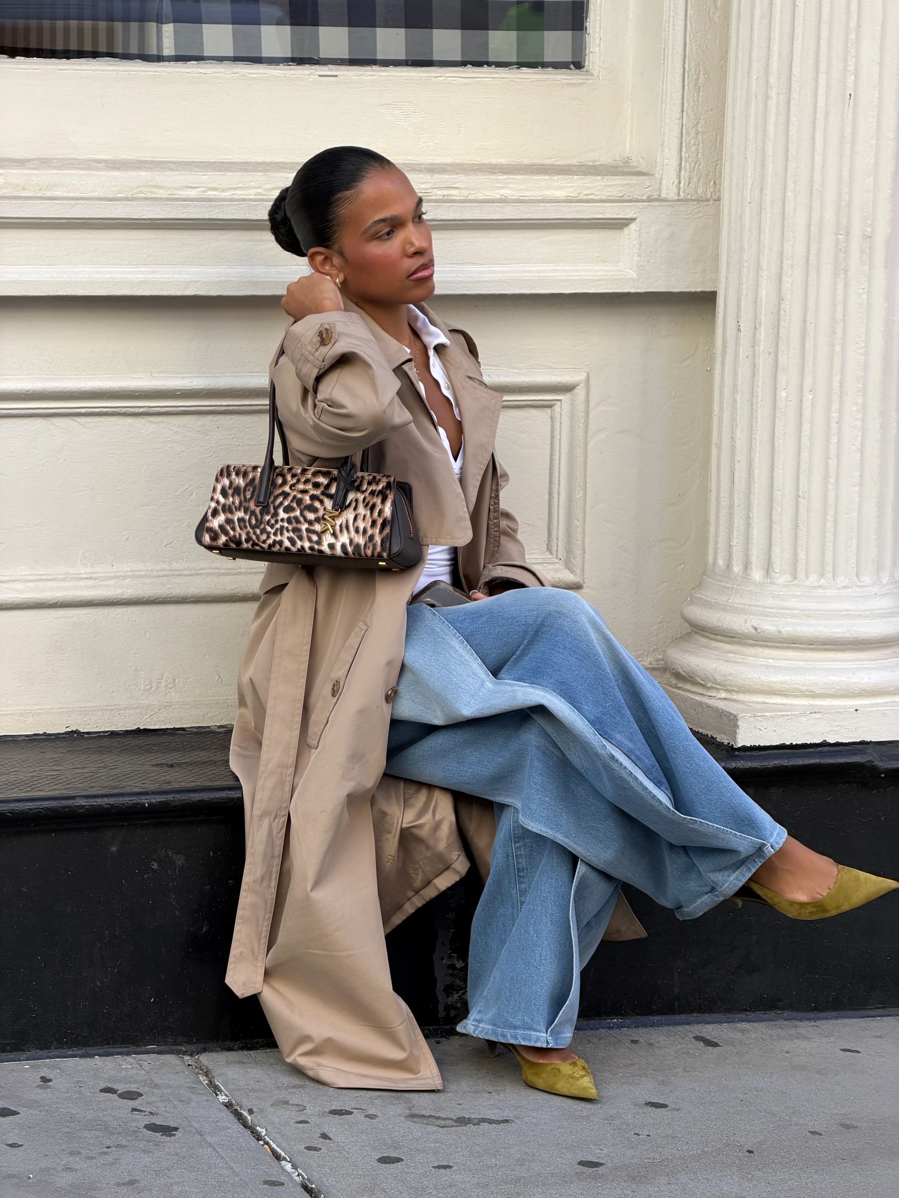 Beige trench coat with wide-leg jeans, leopard print bag, and chartreuse heels.