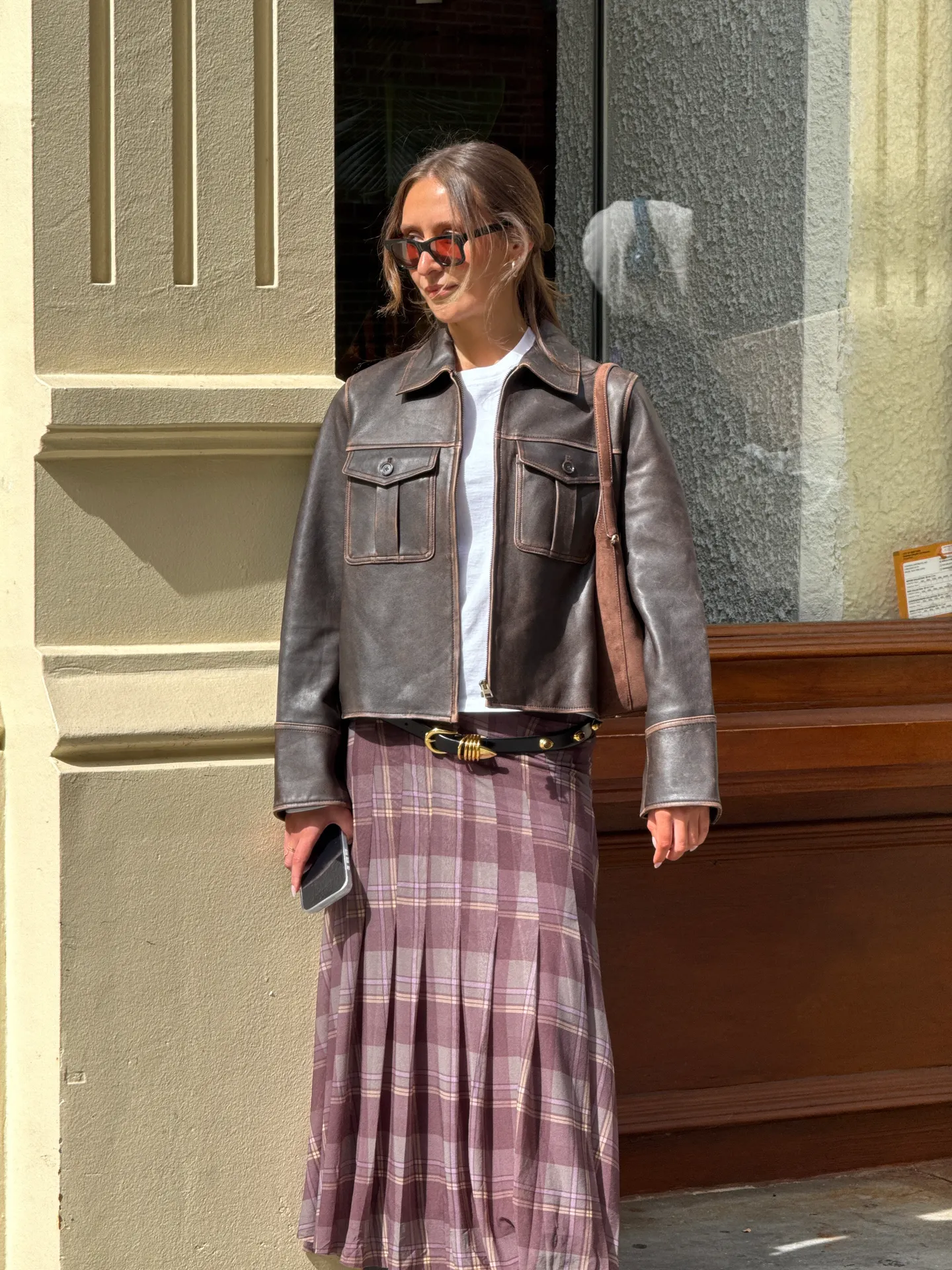 Brown leather jacket, white t-shirt, and purple plaid pleated skirt.