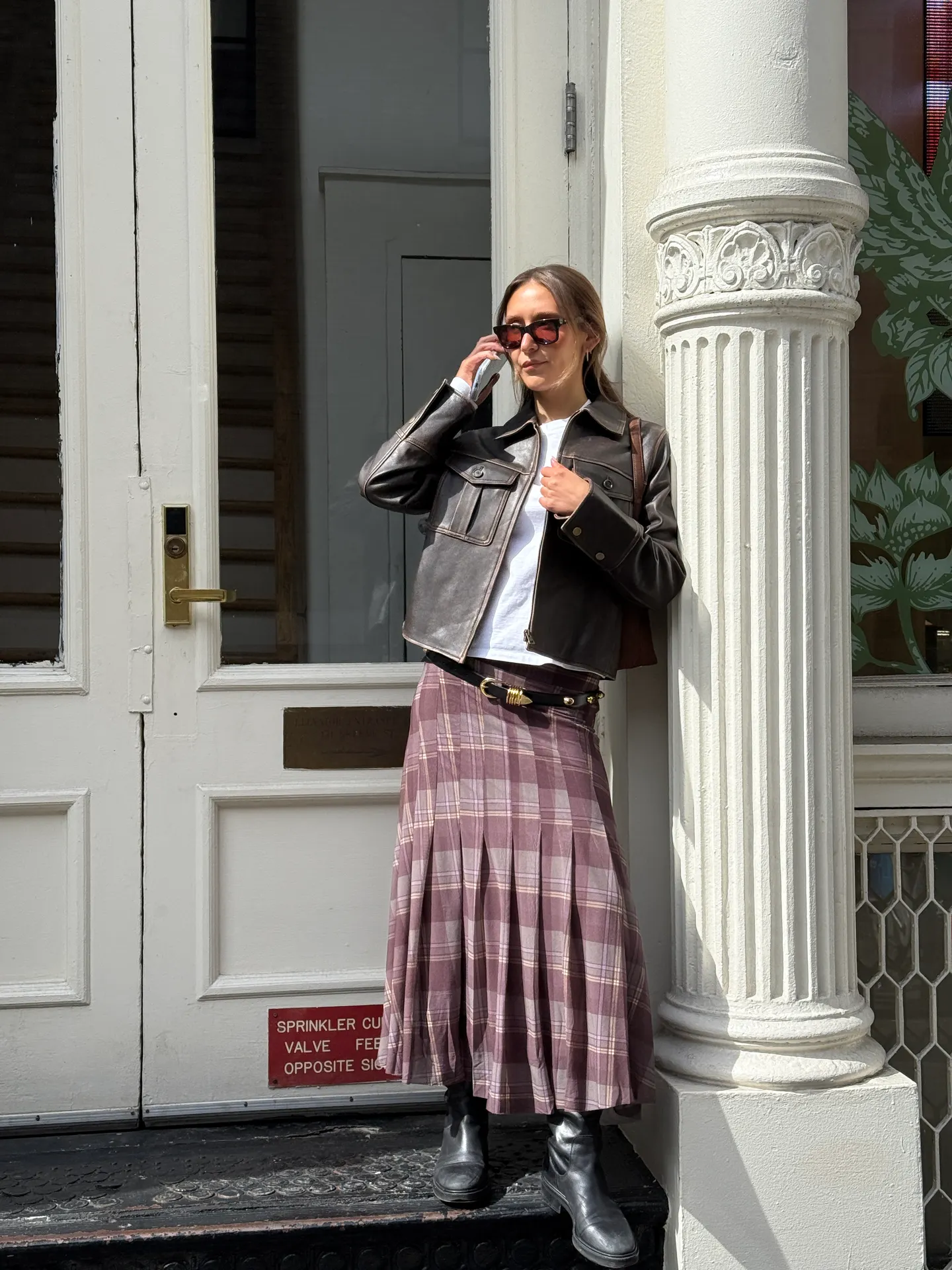 Dark brown leather jacket, white tee, purple plaid maxi skirt, and black boots.