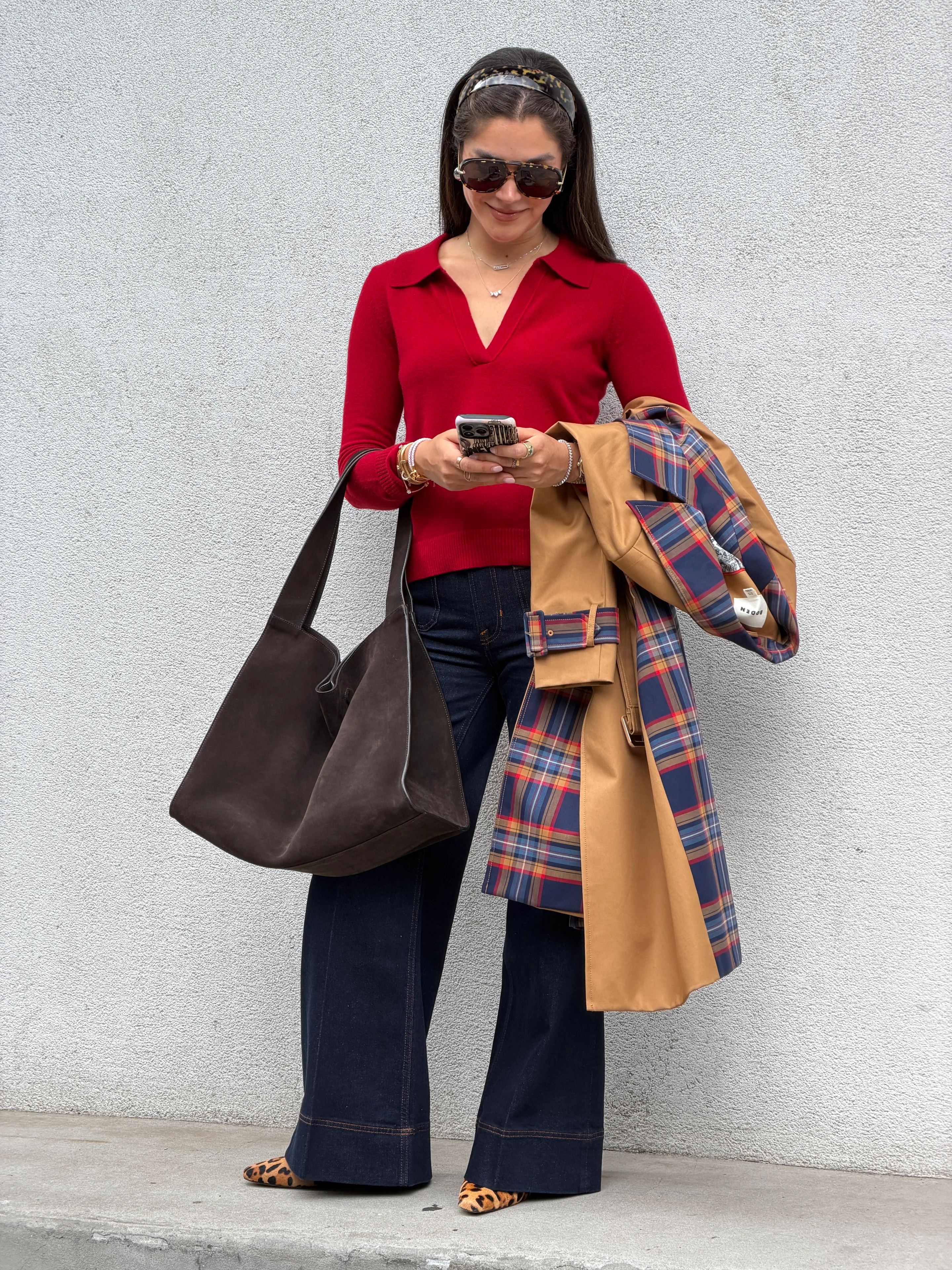 Red polo sweater, wide-leg jeans, leopard flats, and a tan plaid trench coat.