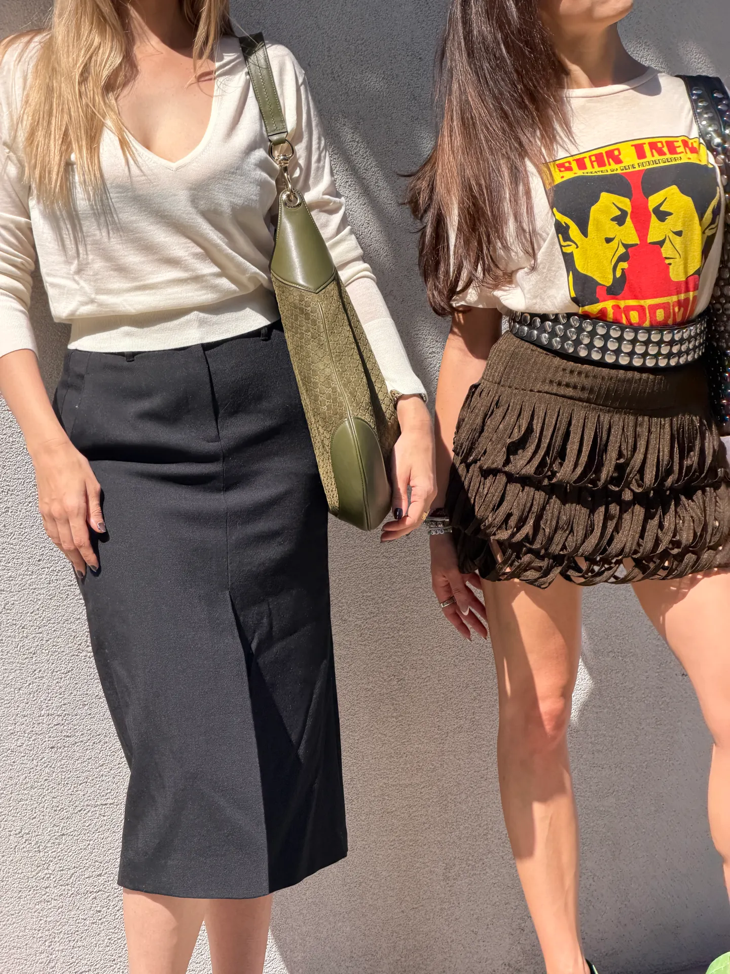 White V-neck sweater, black midi skirt, olive green bag; Star Trek tee, studded belt, fringe mini skirt.